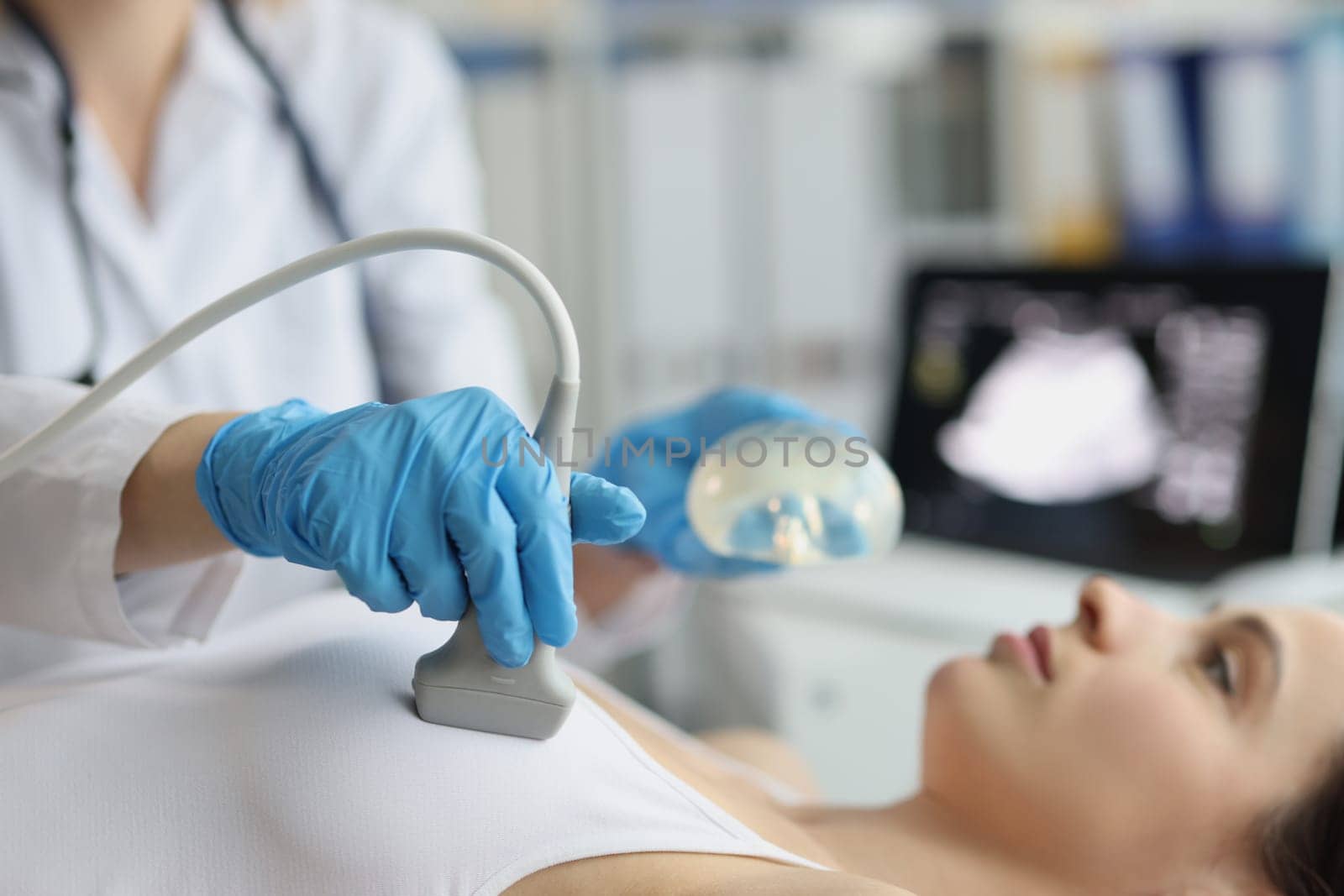 Female doctor examines woman breasts using ultrasound machine. Ultrasound of mammary glands and consultation of doctor in mammologist on breast silicone implants
