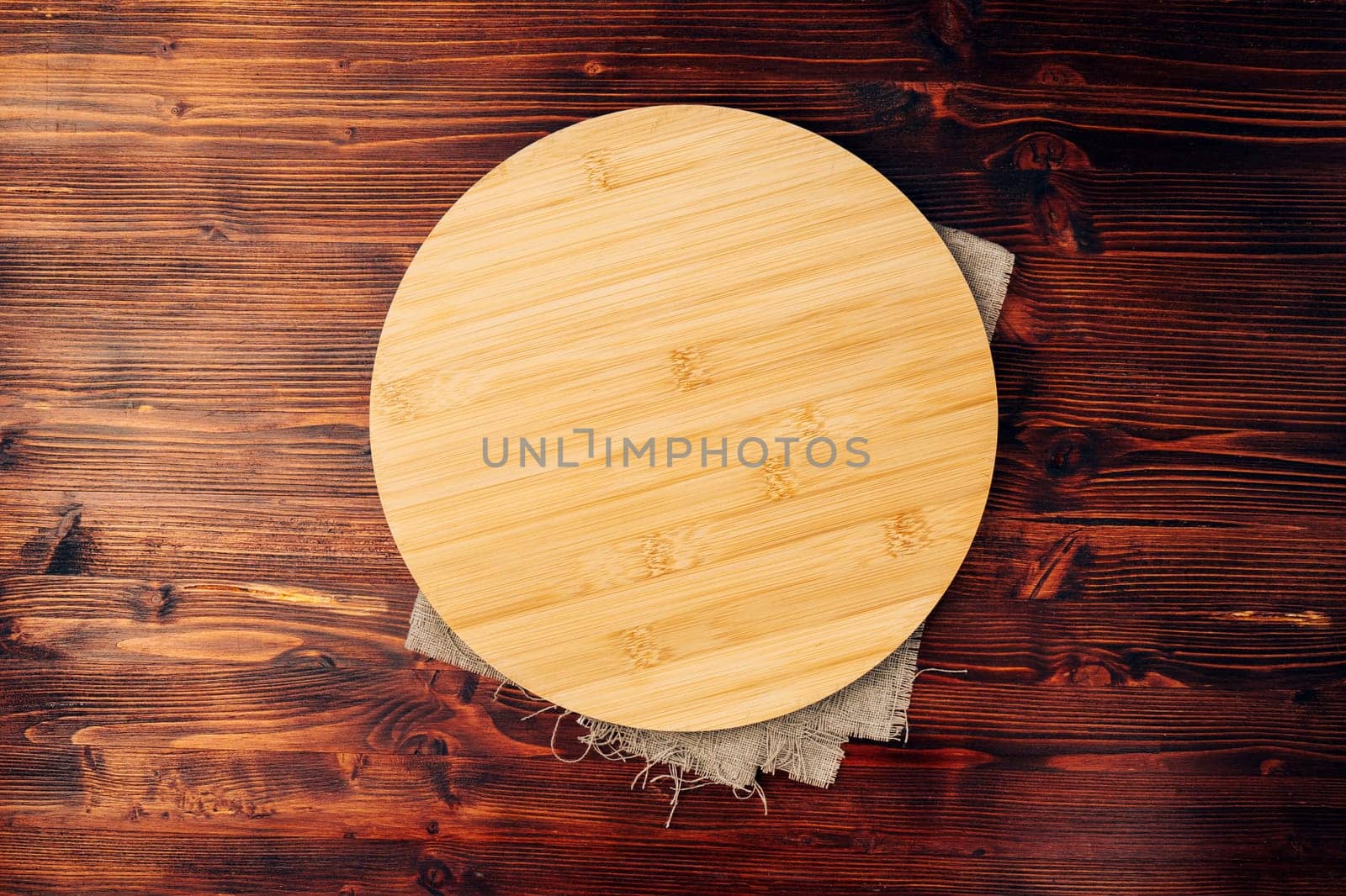Round cutting board on a wooden kitchen table. Free space for your decoration
