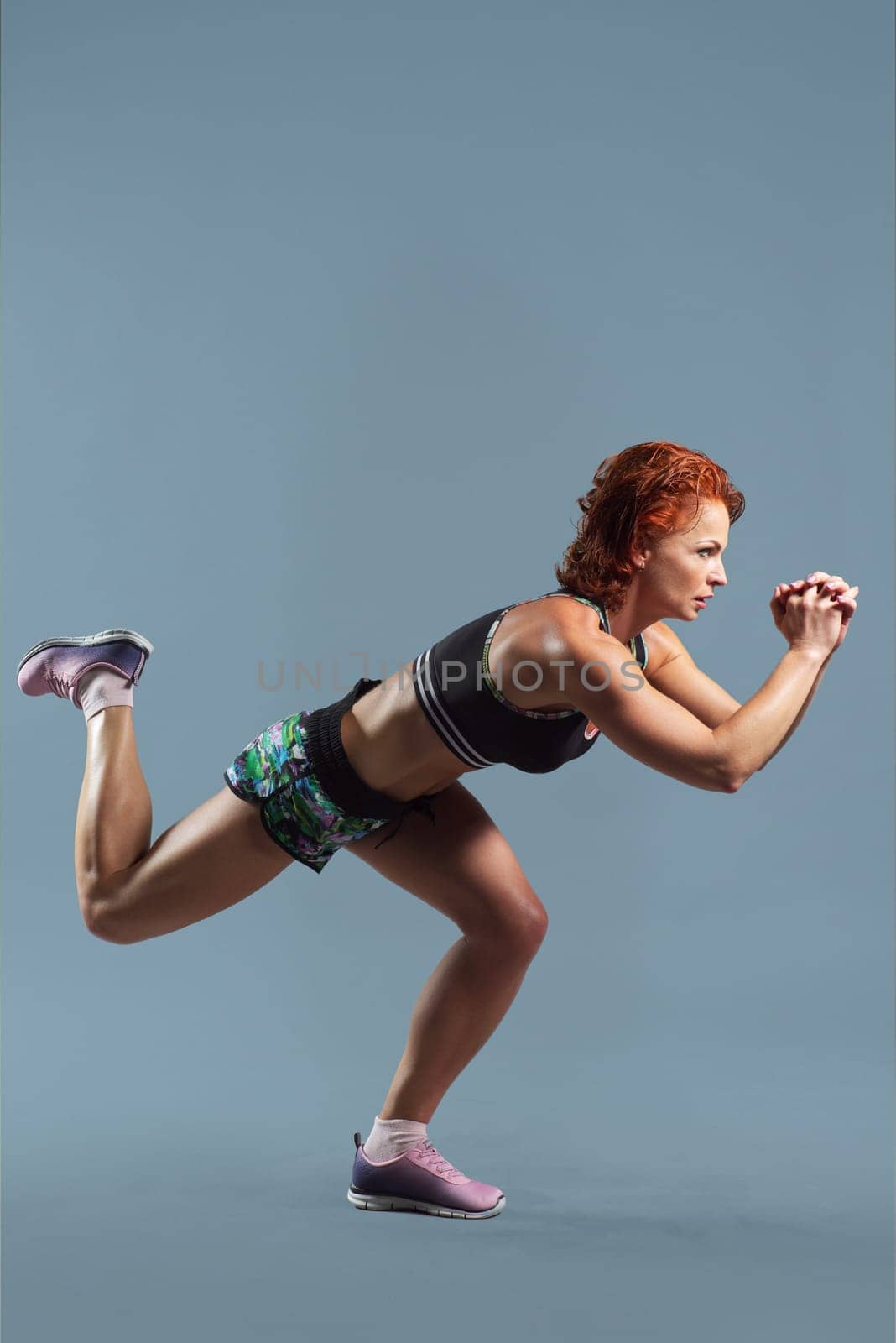 Mature athletic redhead woman in sportswear t-shirt and shorts doing fitness exercises by VH-studio