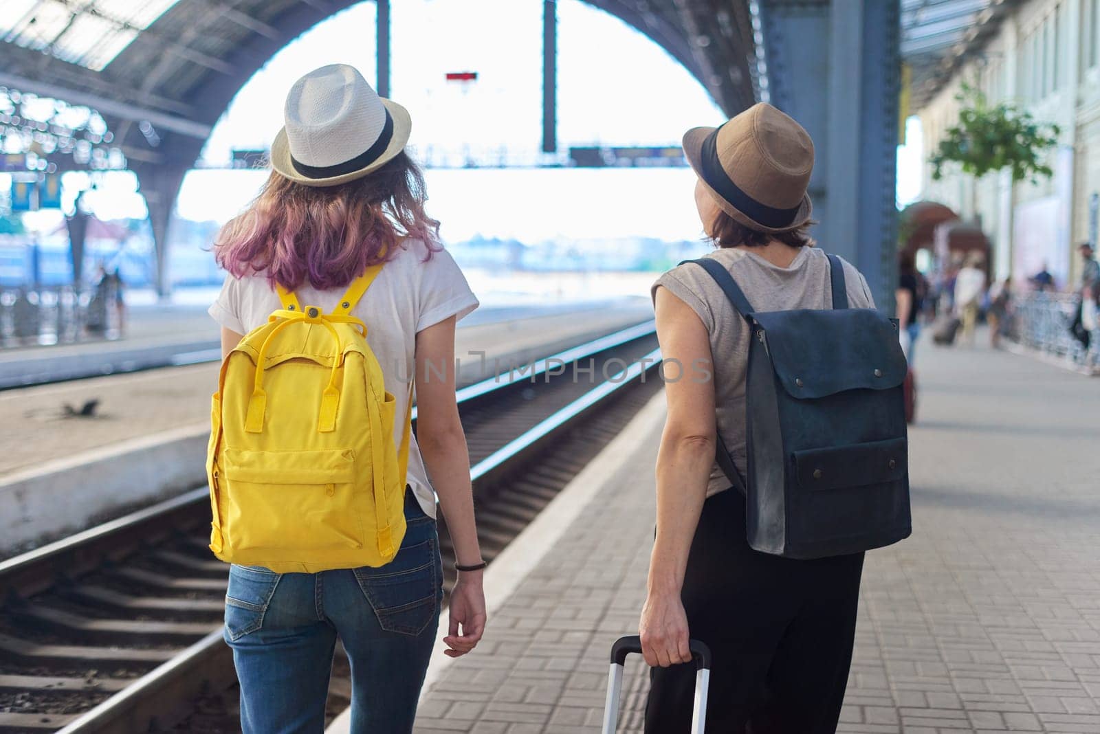 Mother and daughter teenager with backpacks suitcase walking in train station by VH-studio