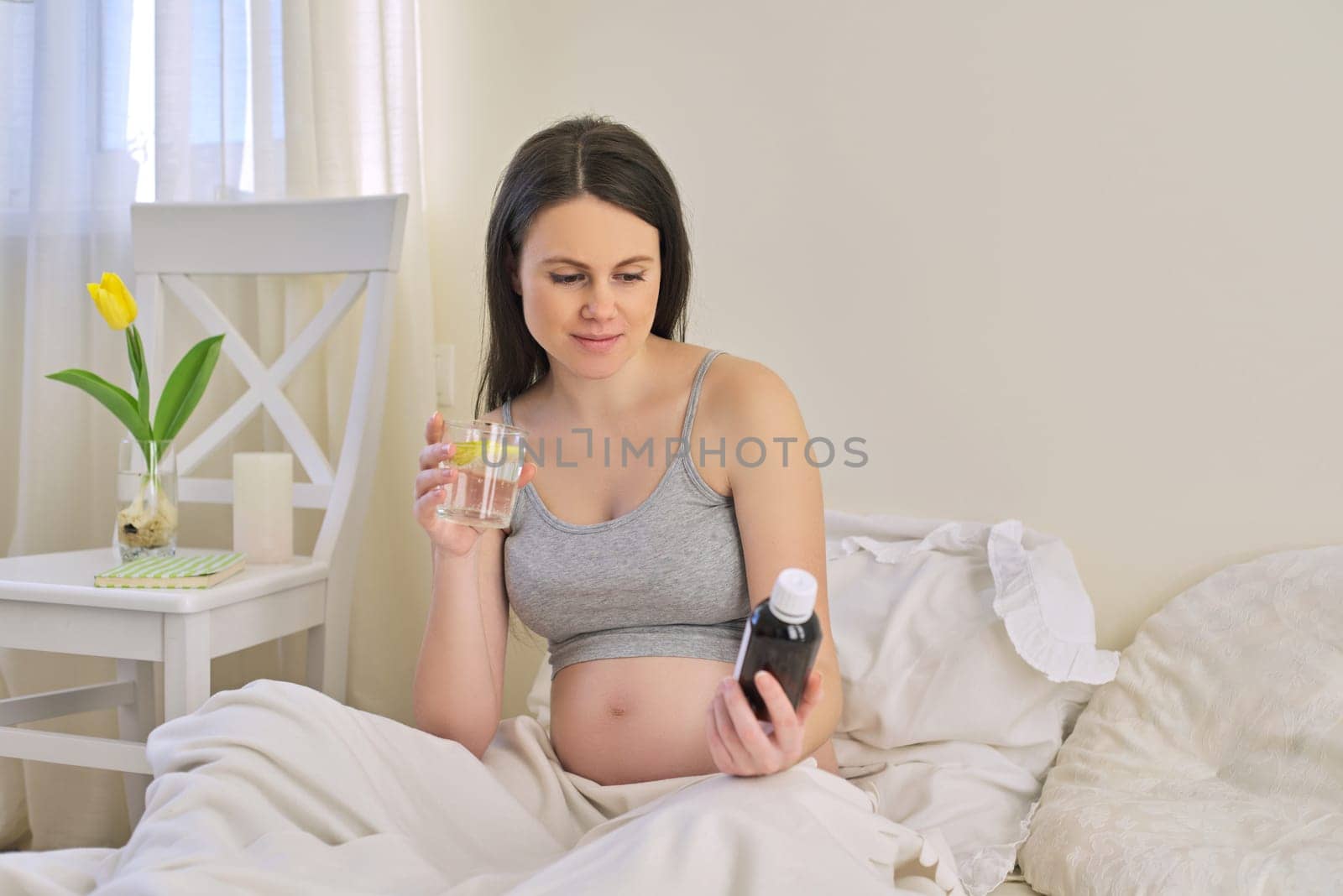 Pregnant woman reading label on bottle with medicine, with vitamins by VH-studio