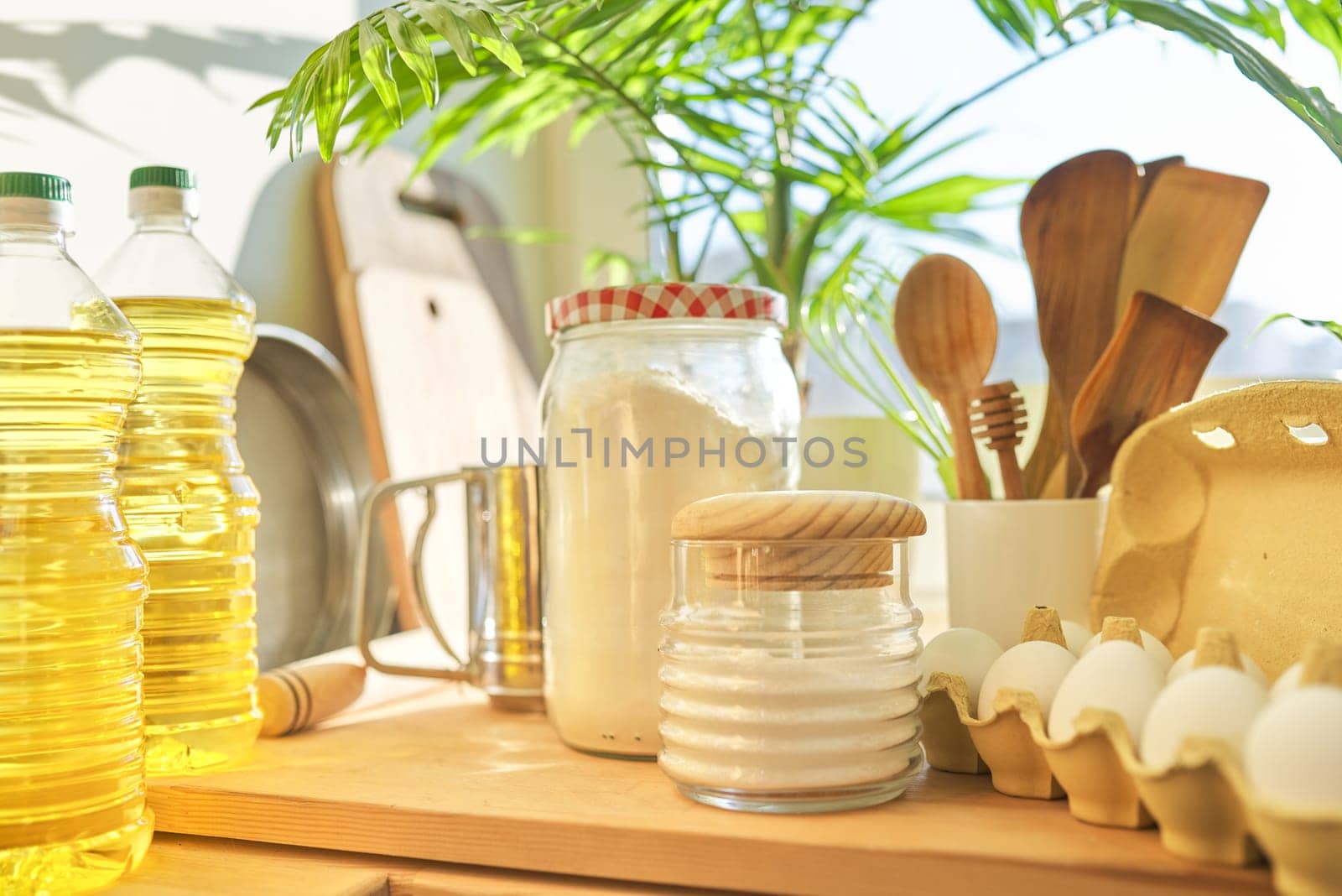 Kitchen utensils, sunflower oil, flour, eggs on wooden table in pantry, food storage at home