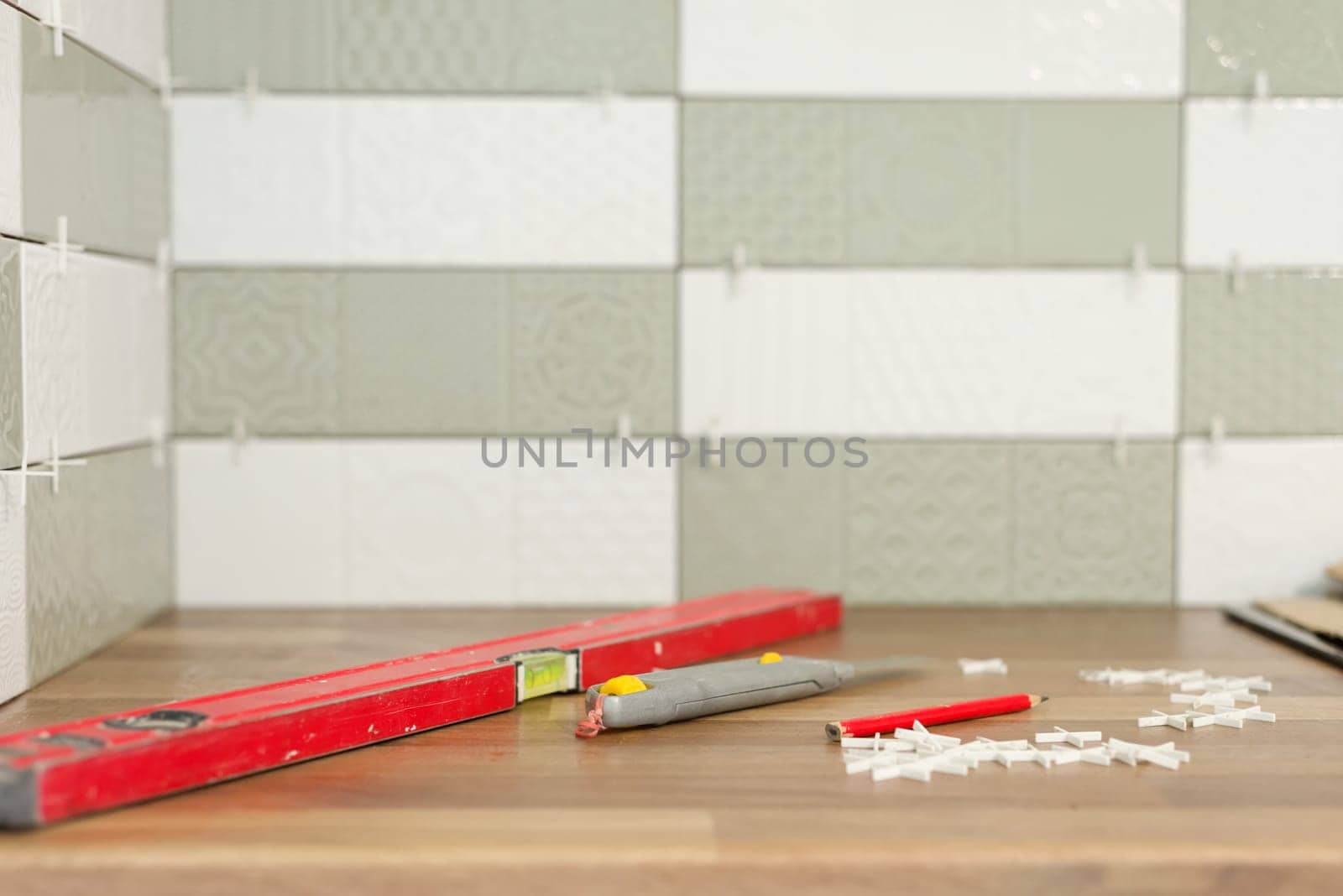 Close-up of tile laying, tiles glued to glue with cement, level fixture for smooth seams, nobody. Renovation, repair, construction