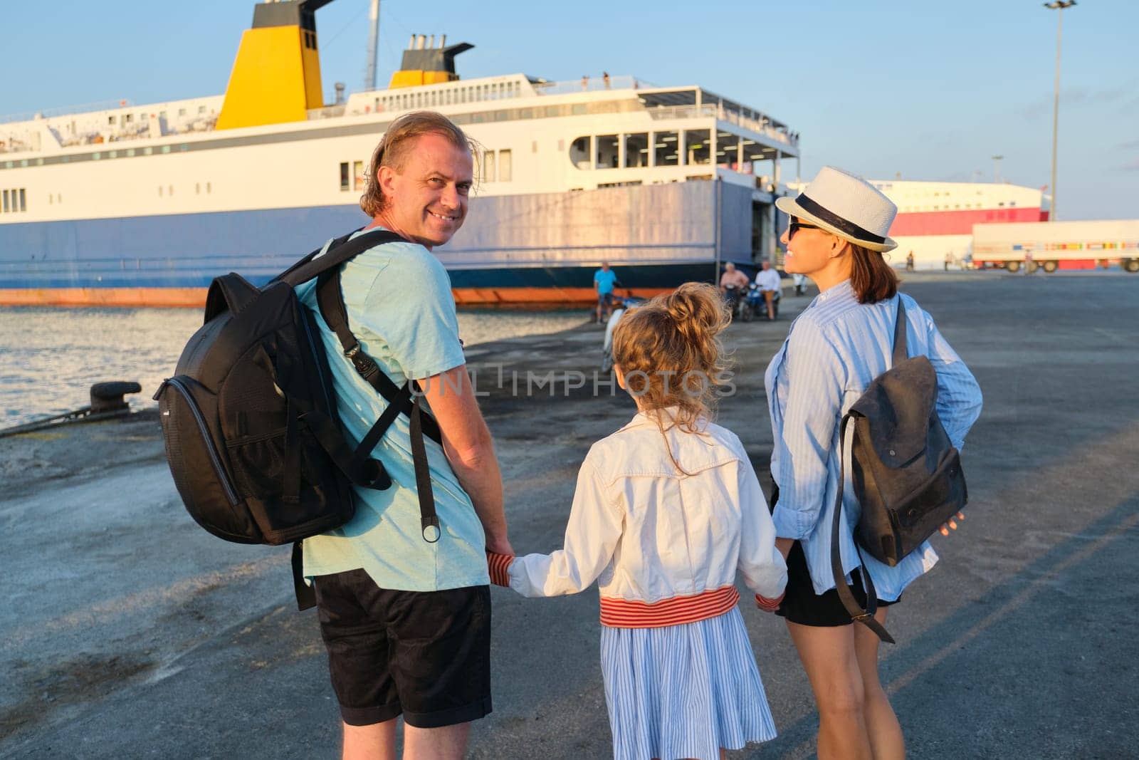 Sea family vacation, mother father and daughter child in seaport holding hands looking at the ferry