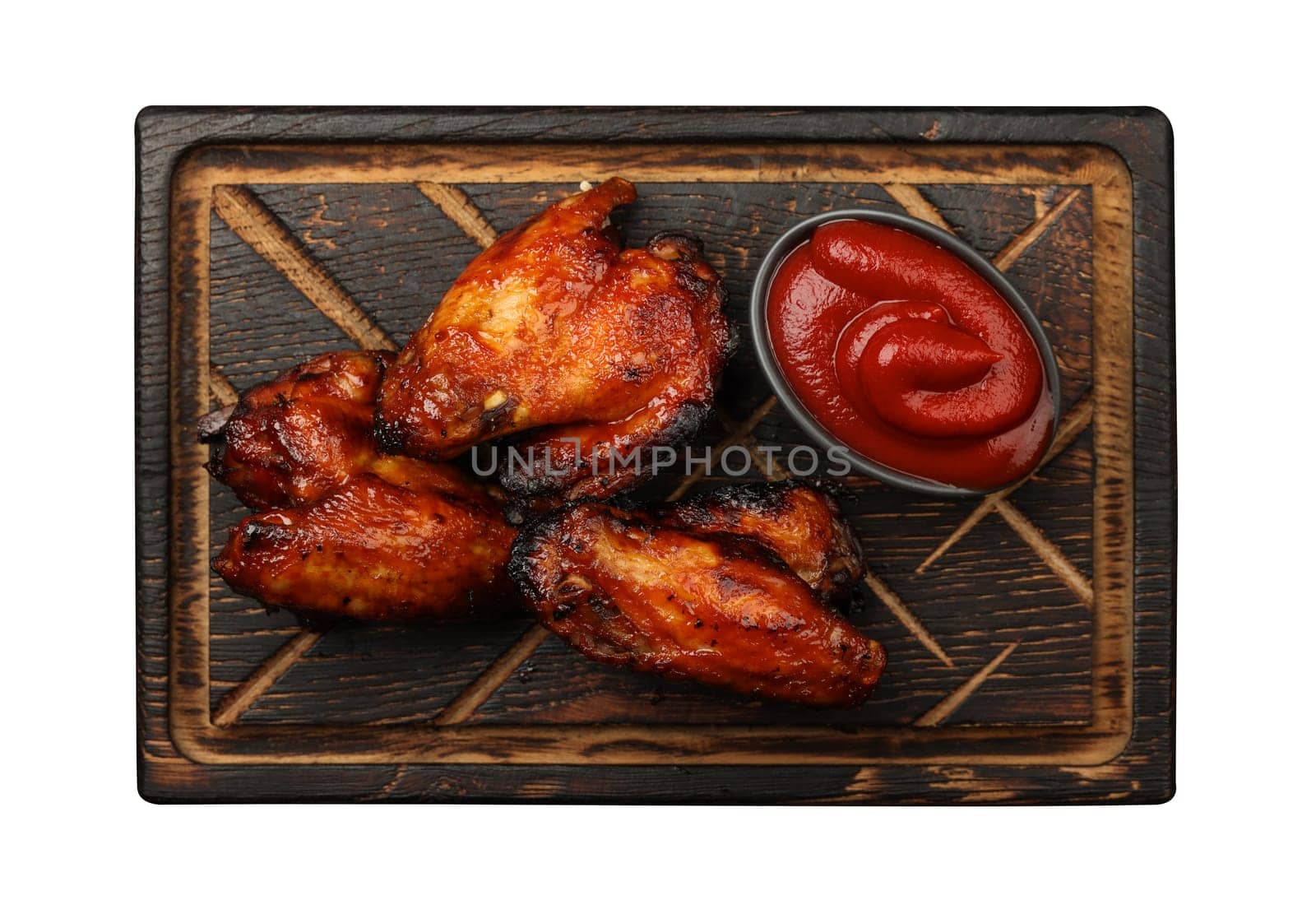 Close up portion of grilled barbecue chicken buffalo wings and BBQ tomato sauce served on wooden board isolated on white background, elevated top view, directly above