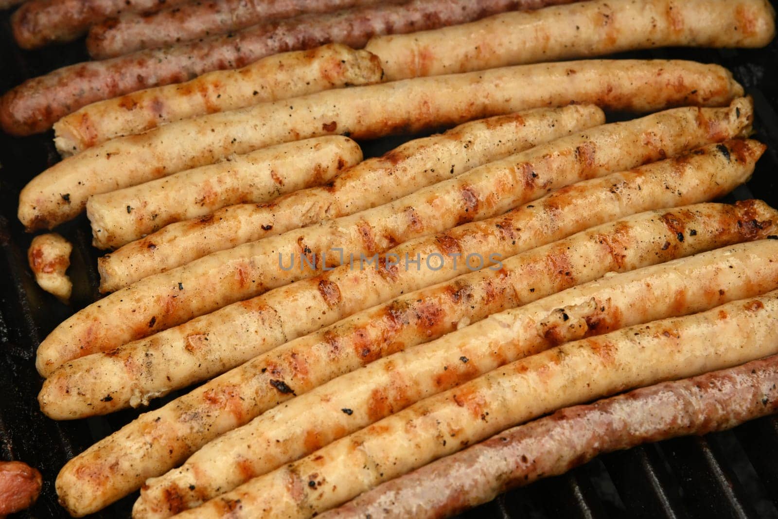 Close up cooking meat sausages on grill, smoking and broiling them, high angle view