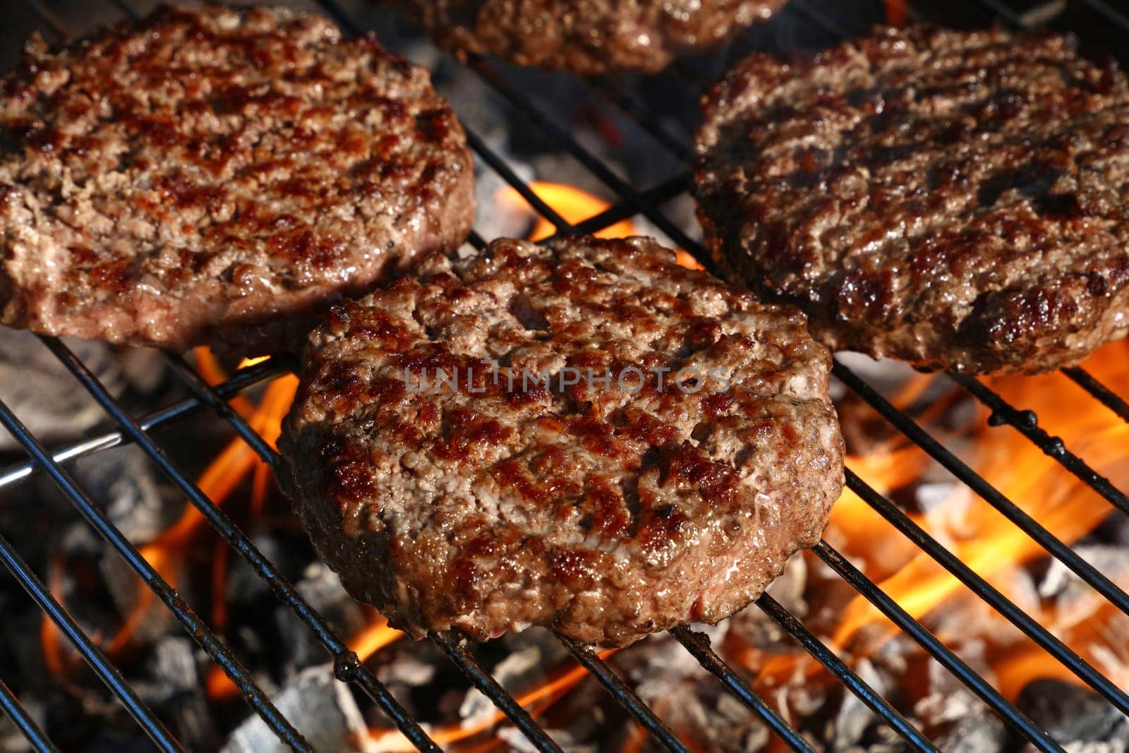 Close up beef or pork meat barbecue burgers for hamburger prepared grilled on bbq fire flame grill, high angle view