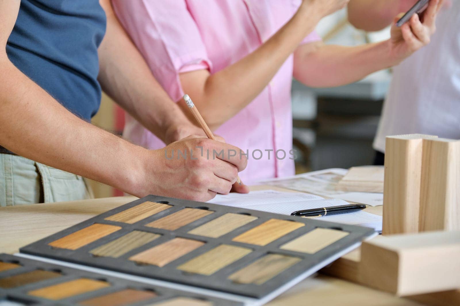 Close up work in carpentry furniture workshop, hands of workers, wooden furniture palette.