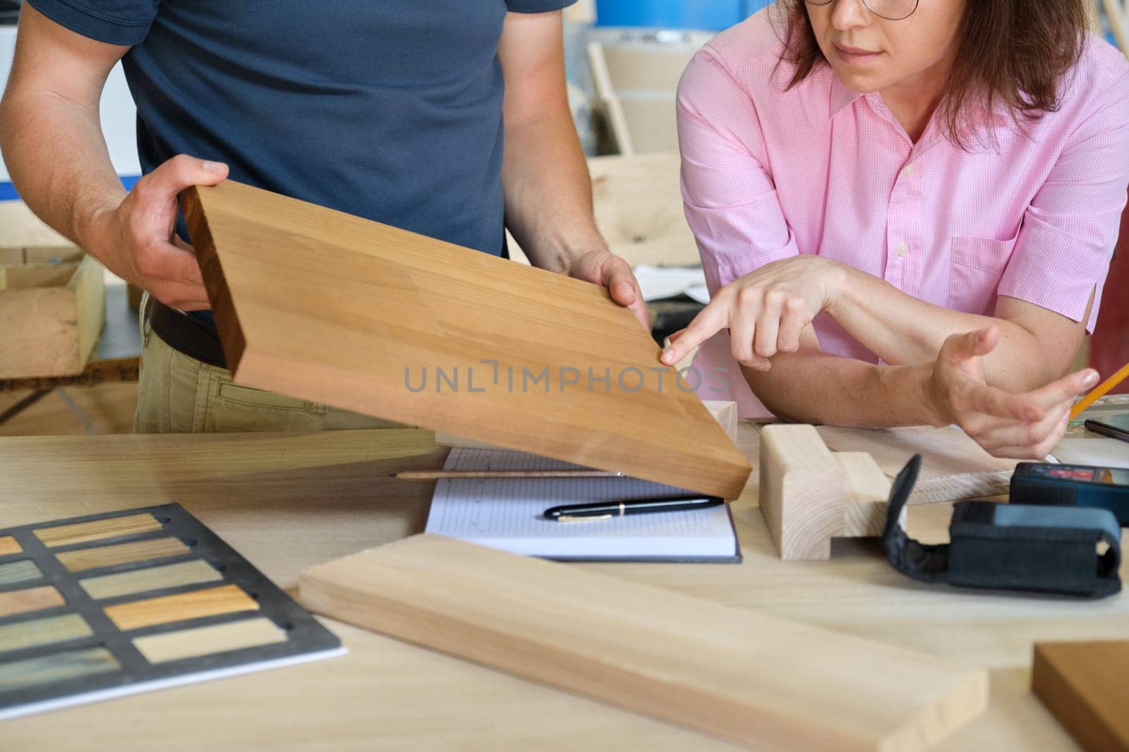 Close up work in carpentry furniture workshop, hands of workers, wooden furniture palette.