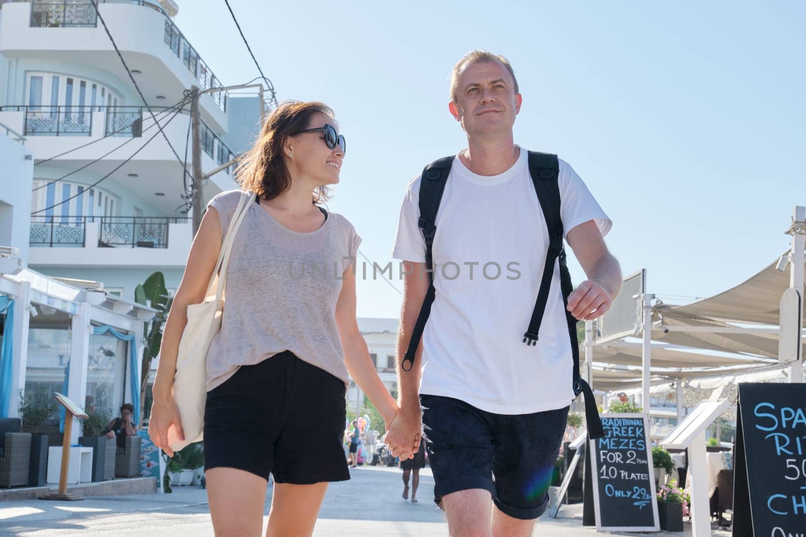 Mature happy couple walking around resort town holding hands. Communication, lifestyle, travel, outdoor activities for middle-aged people