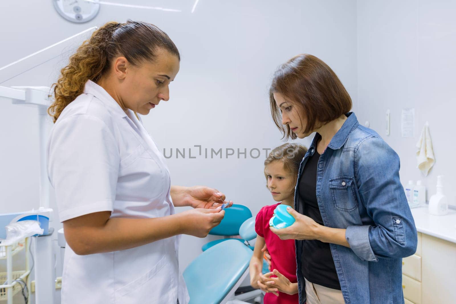 Mother and child girl in meeting with doctor orthodontist, dental examination and dentist consultation. Beautiful smooth healthy white teeth in children