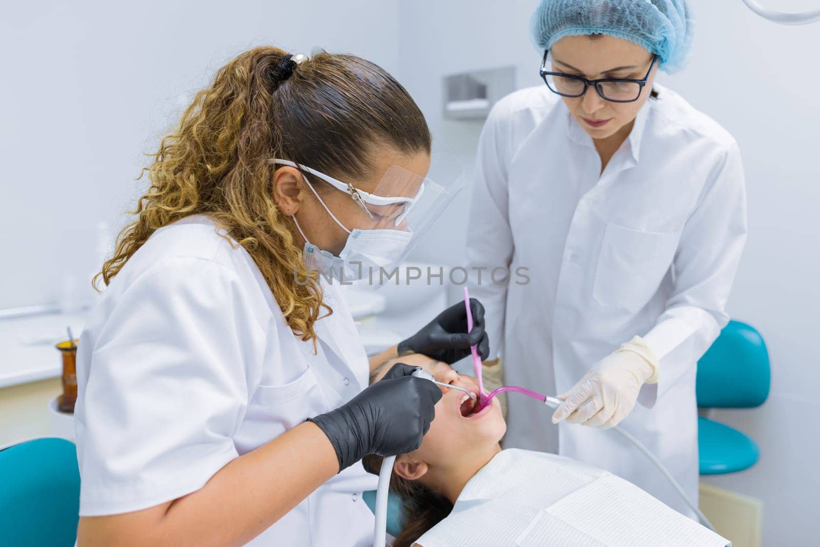 Girl child sitting in dental chair treating teeth by VH-studio