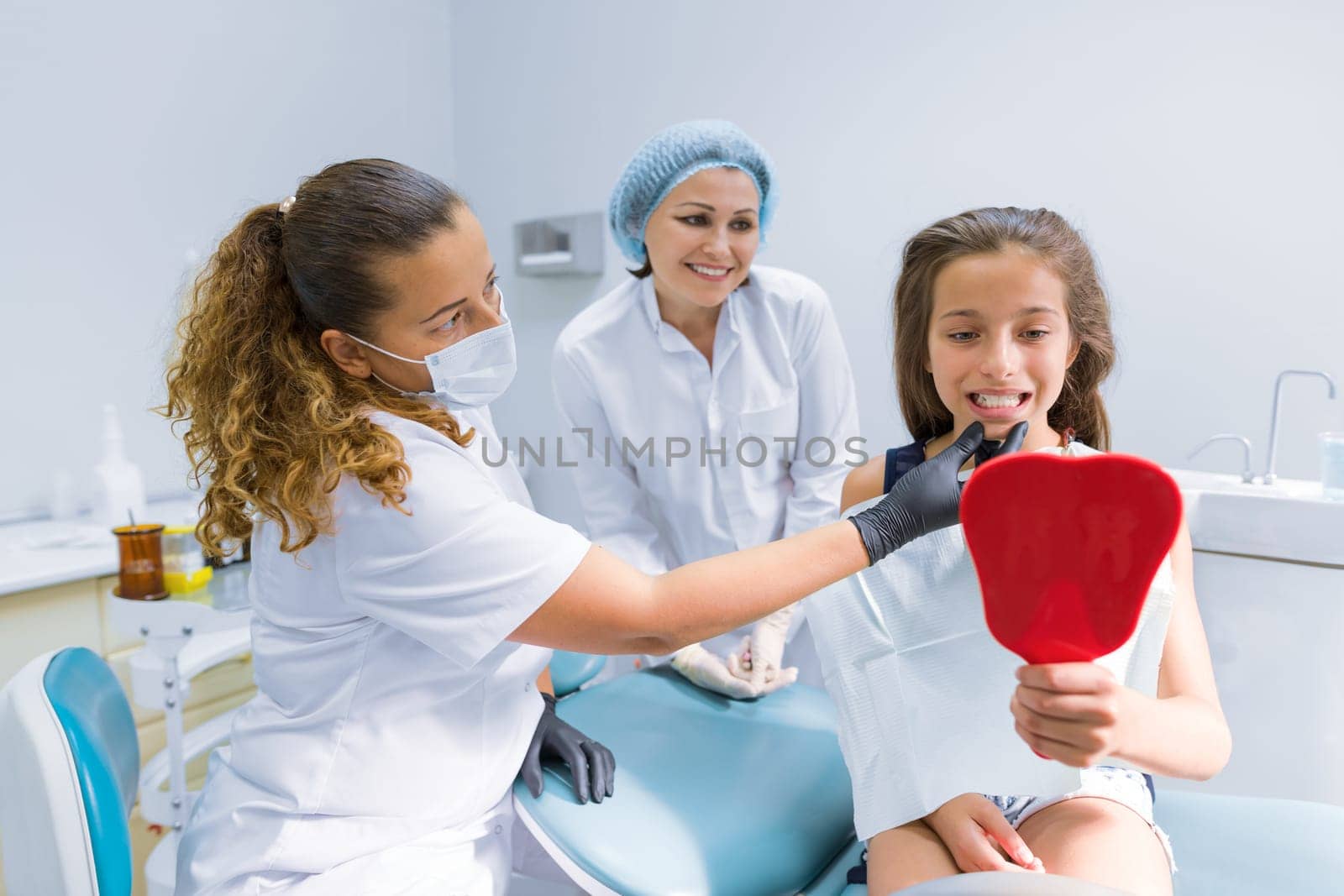 Girl child sitting in dental chair treating teeth by VH-studio