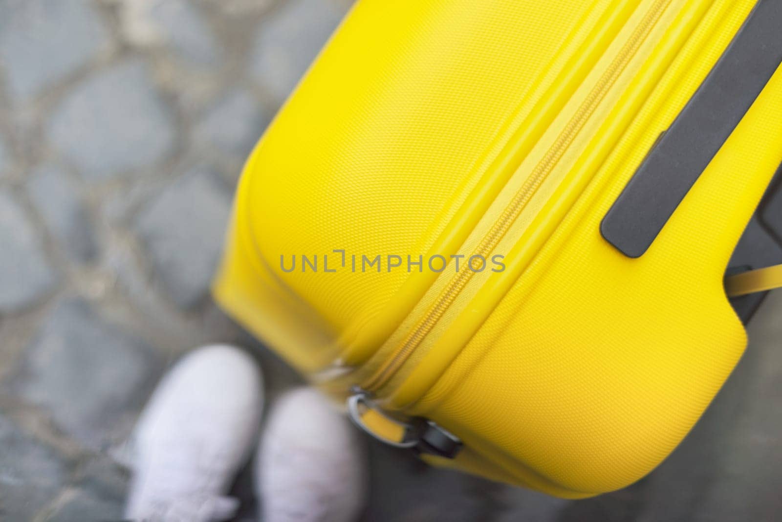 Travel tourism concept, close up of yellow plastic polycarbonate suitcase on tourist city street, copy space