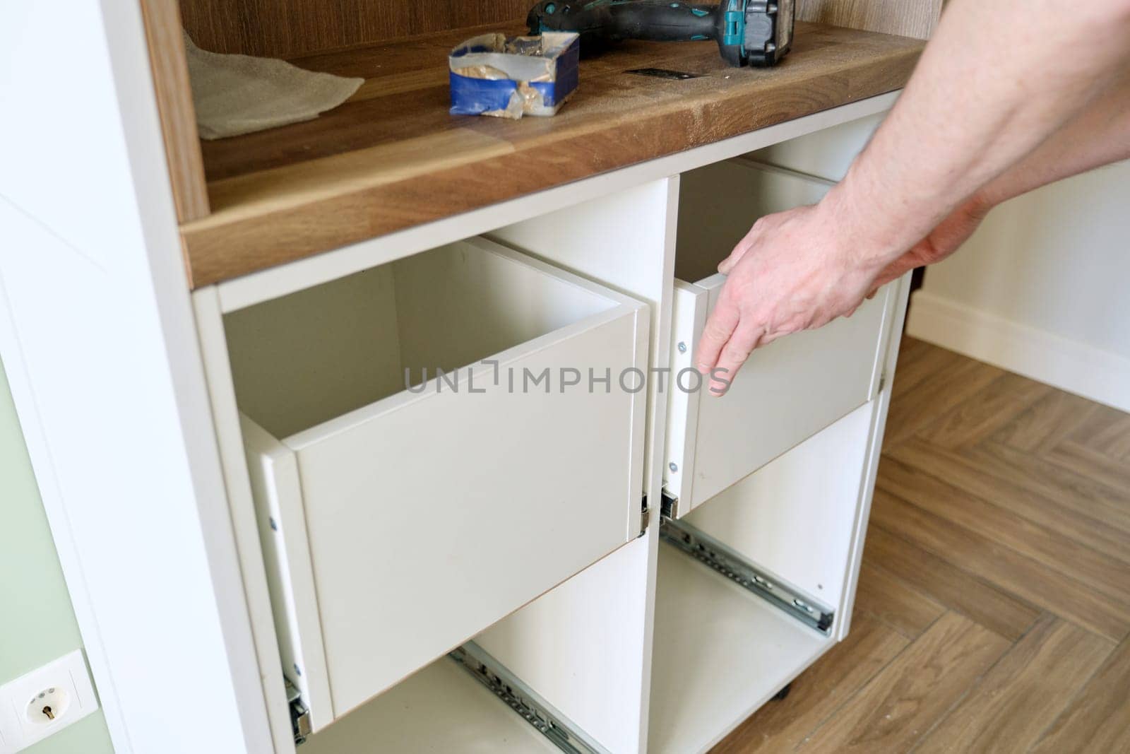 Closeup process of assembling kitchen furniture, hands of male worker. Working hands of male carpenter assembling furniture