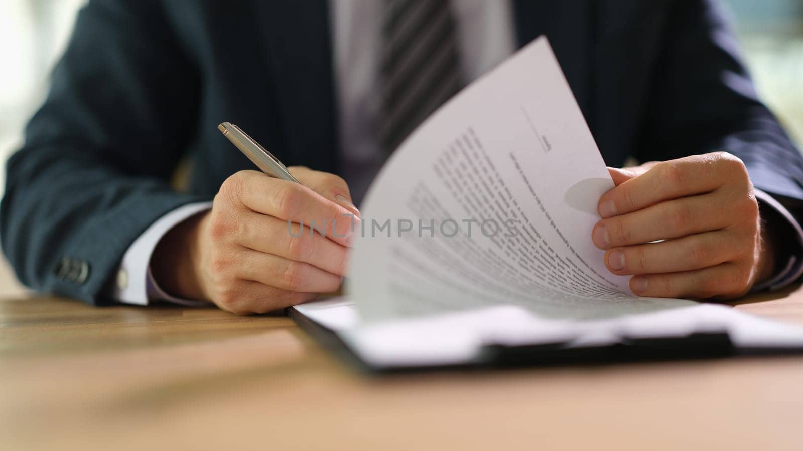 Businessman leafing through documents and signing contract for business deal at work in office closeup by kuprevich