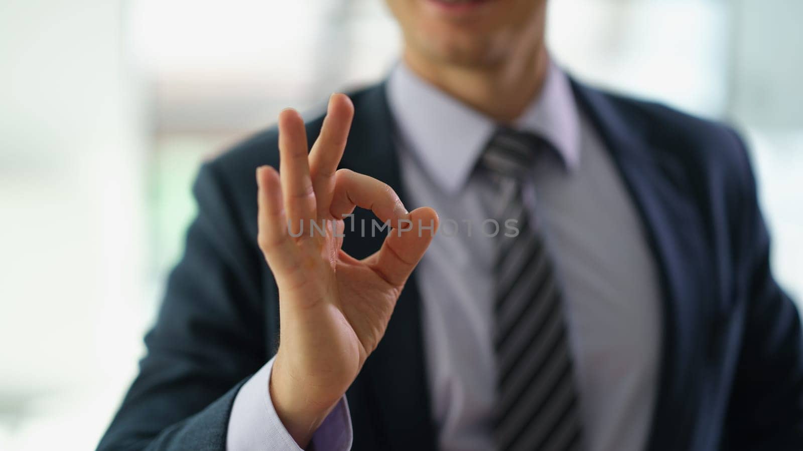 Businessman in suit showing hand gesture ok at work in office closeup. Approve good choice concept