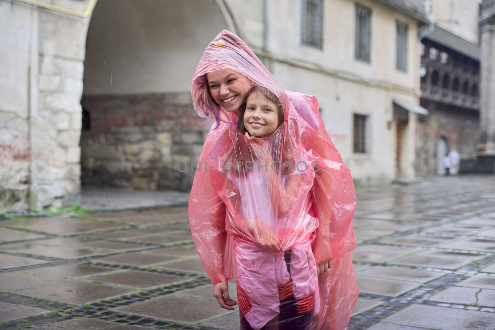 Girls children walking in the tourist city in the rain dressed in a raincoat