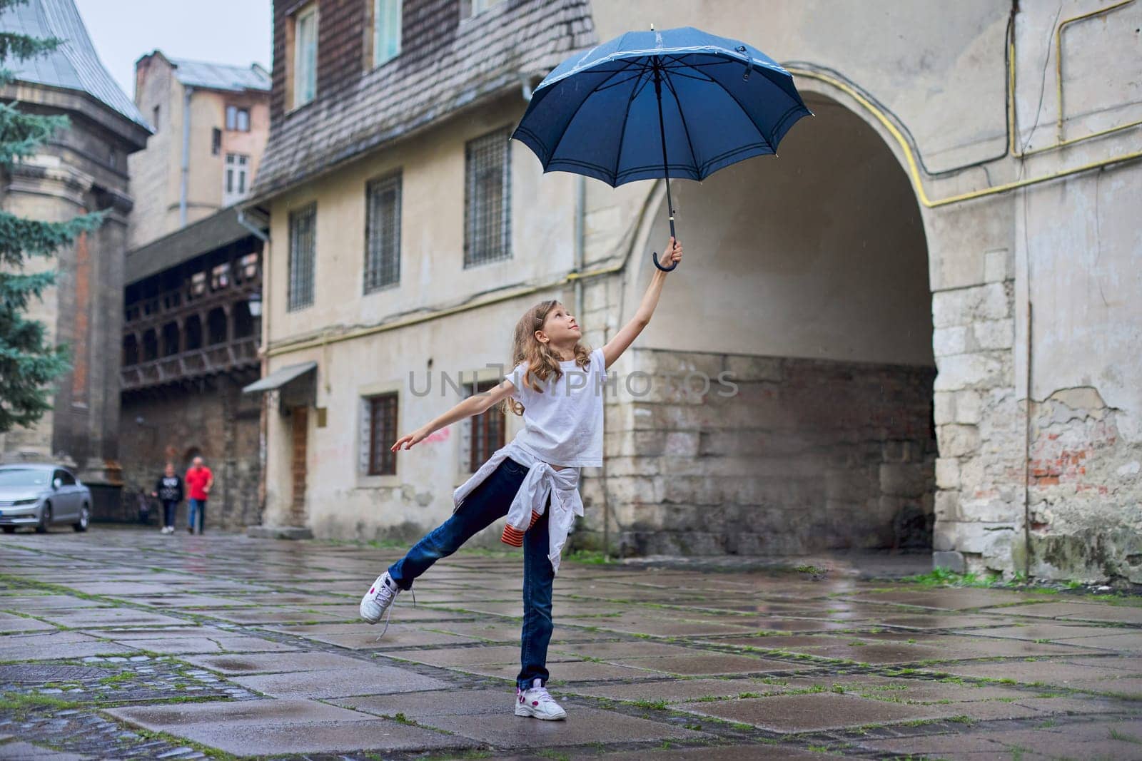 Little girl child in the rain with an umbrella, tourist old city background by VH-studio