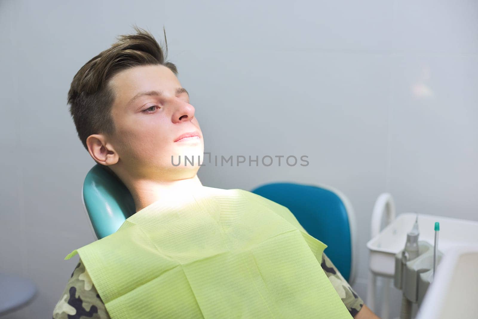 Boy sitting in dental chair at the clinic, teenager visits dentistry