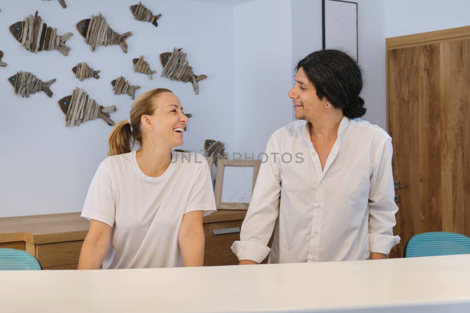 Portrait of spa hotel workers, man and woman near reception, bright interior of resort hotel background