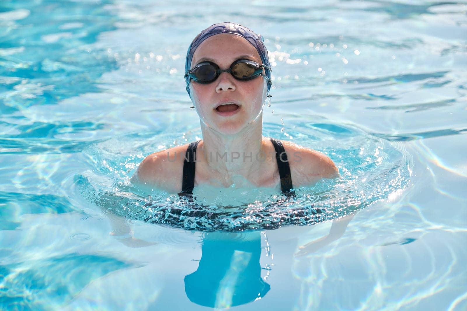 Face of young women swimmer in pool, girl in cap goggles for swimming. Active sports healthy lifestyle of youth