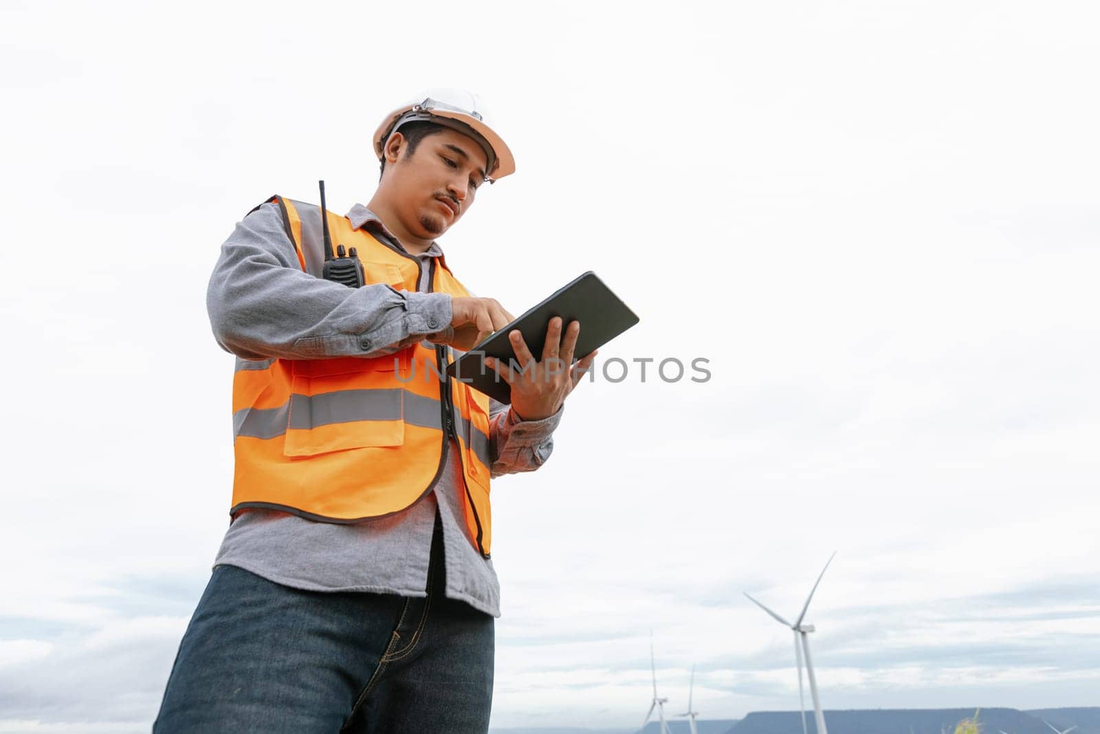 Engineer working on a wind farm atop a hill or mountain in the rural. Progressive ideal for the future production of renewable, sustainable energy. Energy generation from wind turbine.