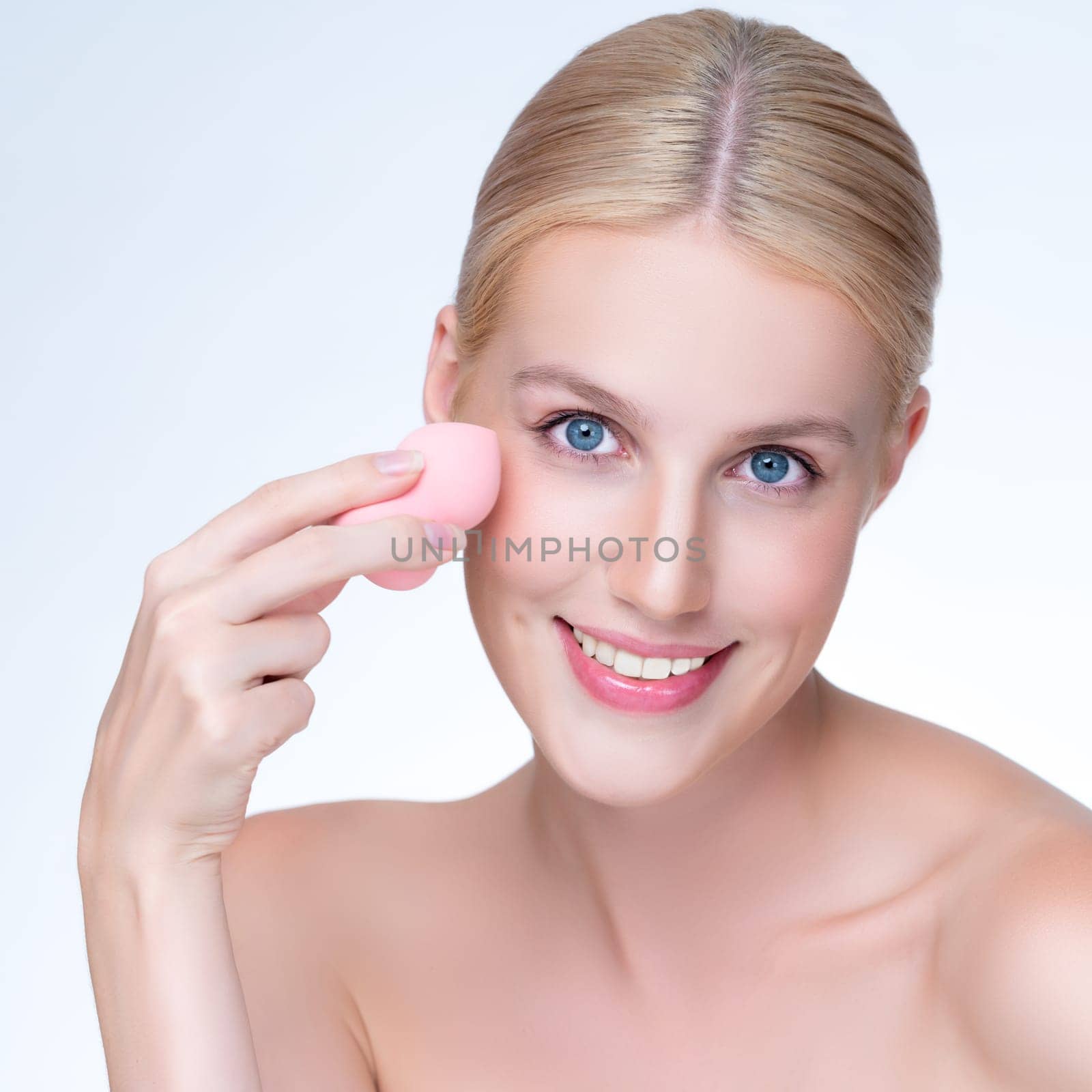 Personable beautiful natural makeup woman using powder puff for facial makeup. by biancoblue