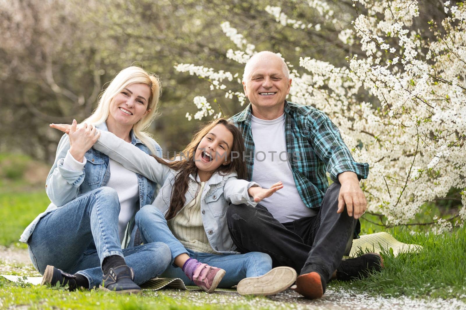 family having picnic in park, garden with flowering trees, spring.