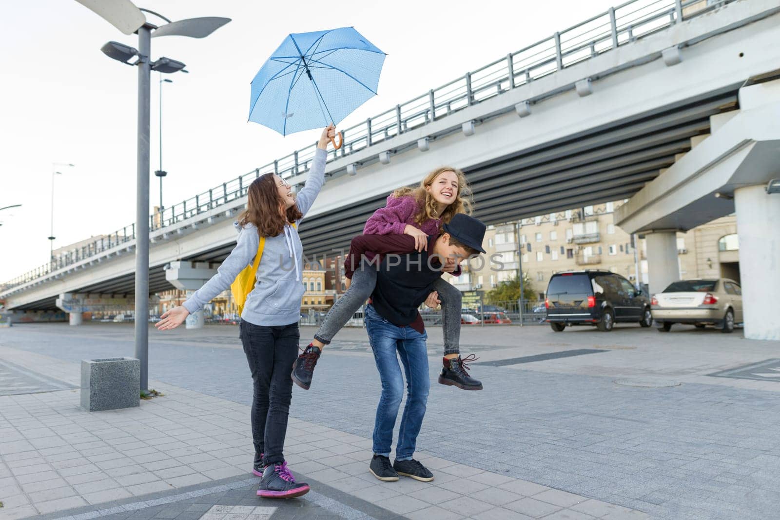 Group of teenagers friends having fun in the city, laughing kids with umbrella by VH-studio