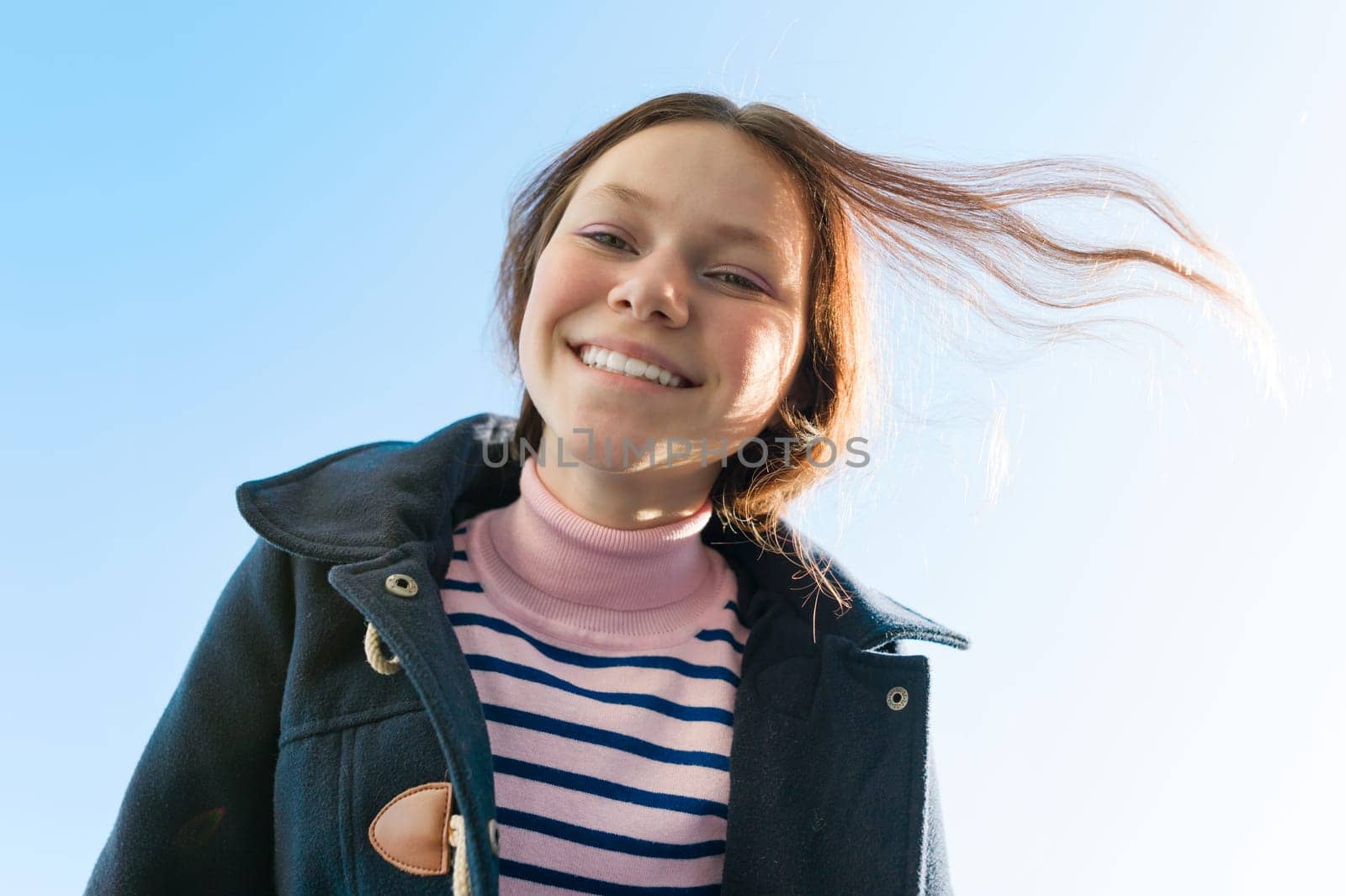 Portrait of a young smiling teen girl, background blue sky.