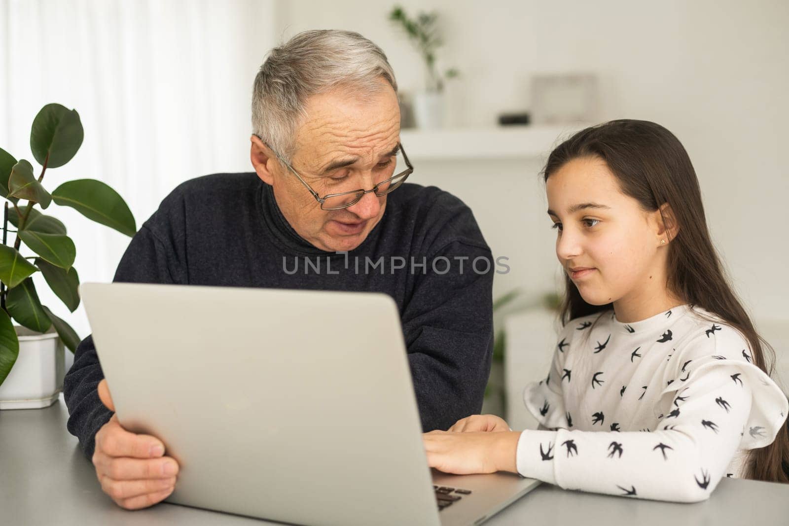 Grandfather and granddaughter spend time together use laptop, browse website, younger generation teach explain to older how to use modern tech concept.