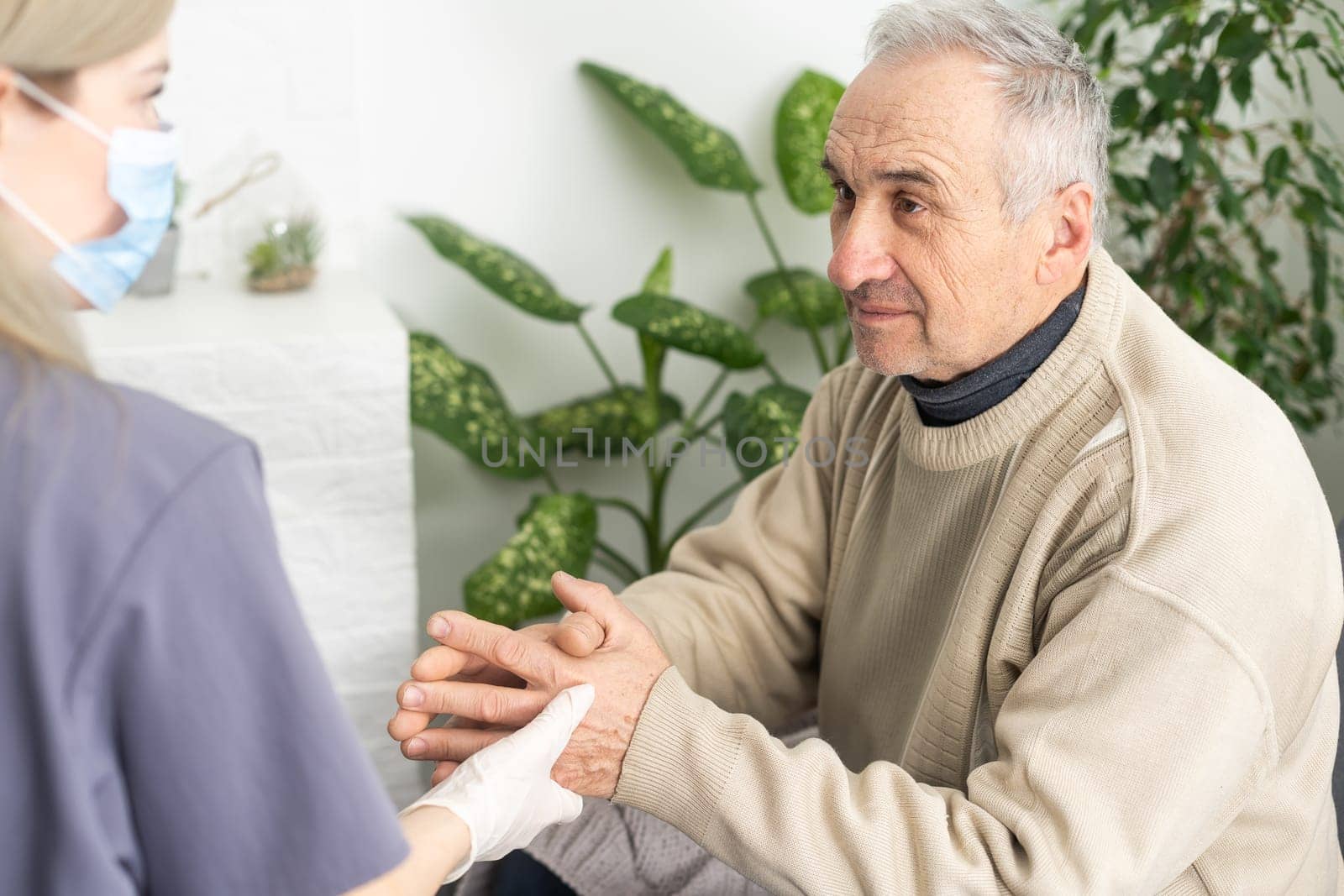 Caring nurse talks to old patient holds his hand sit in living room at homecare visit provide psychological support listen complains showing empathy encouraging. Geriatrics medicine caregiving concept.