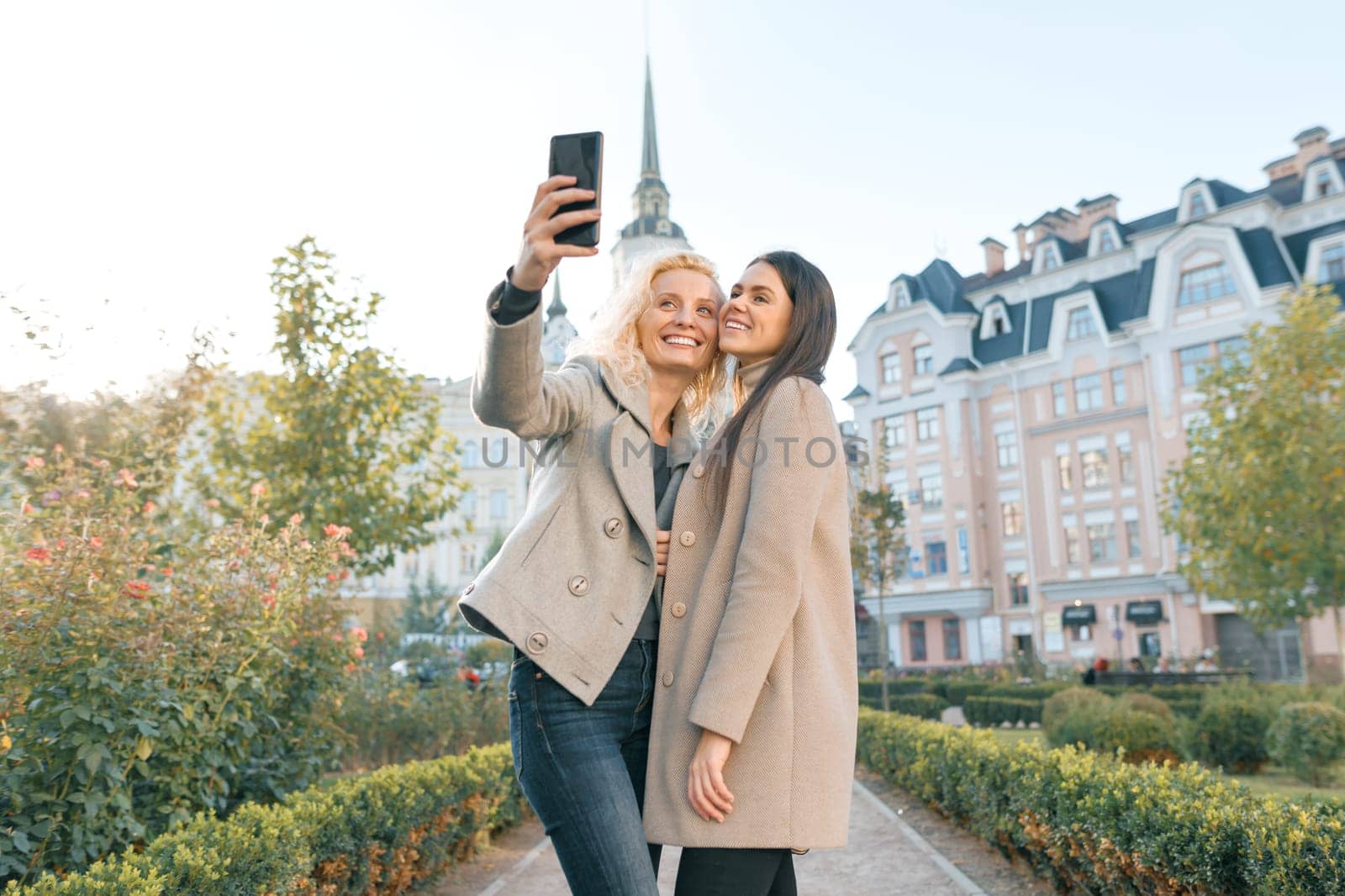 Two young women having fun, looking at the smartphone laughing by VH-studio