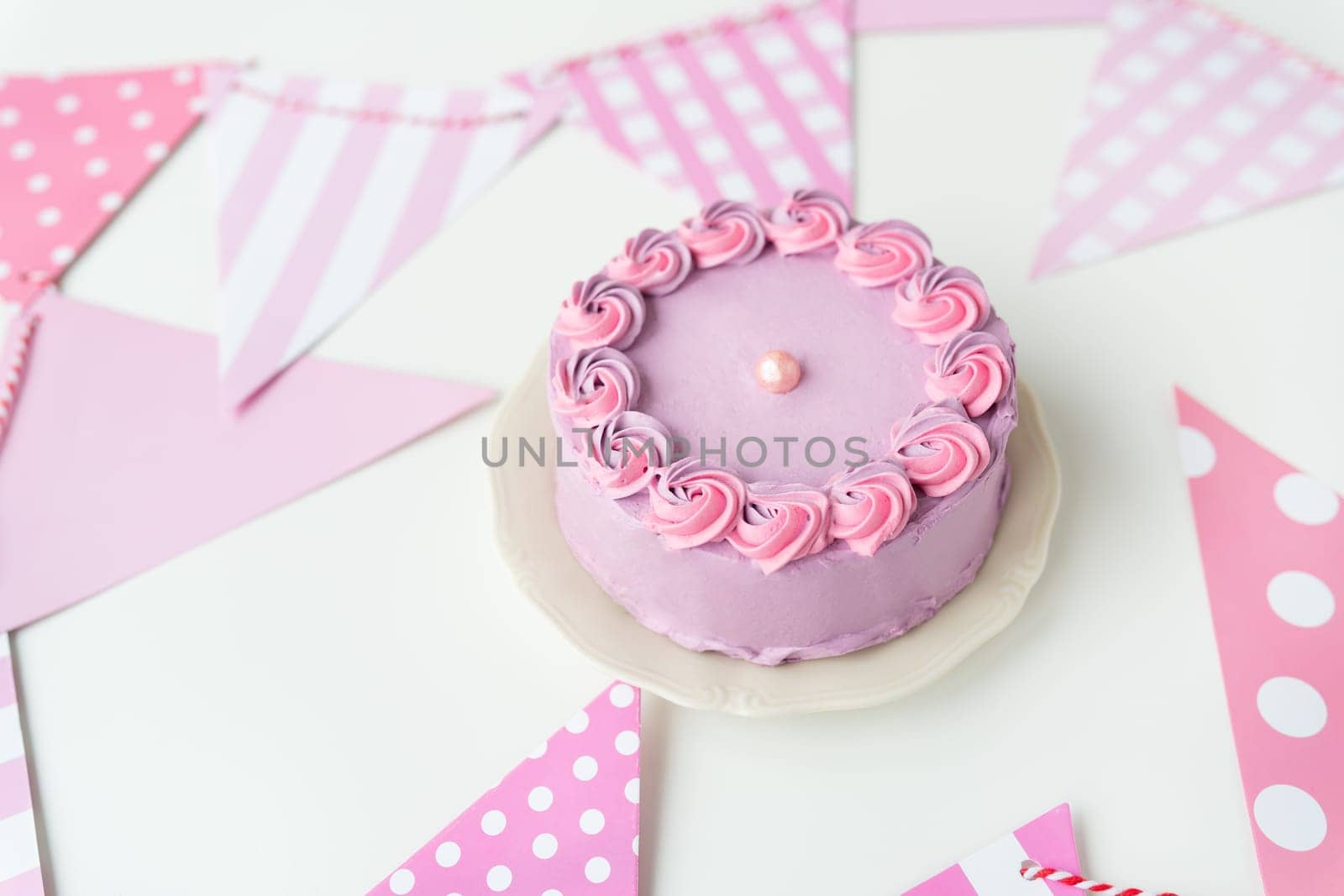 Delicate lavender pink bento cake on a plate against a background of flags for a party. Celebration, happy day. by sfinks