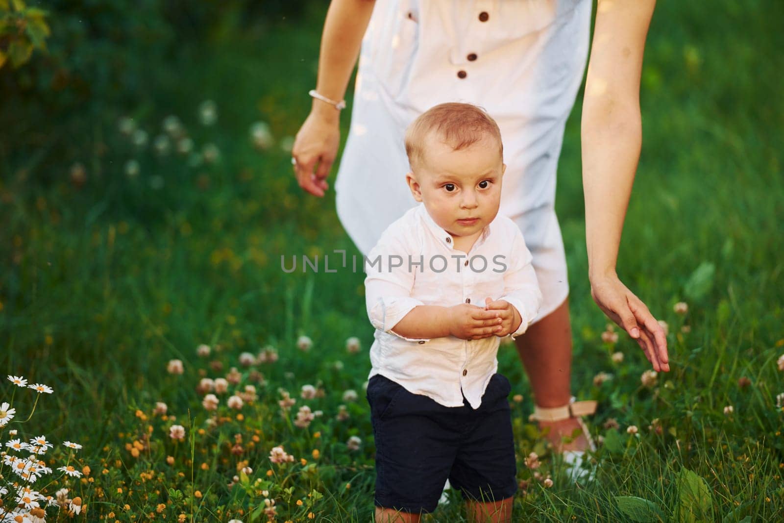 Happy mother with her son spending free time on the field at sunny day time of summer.