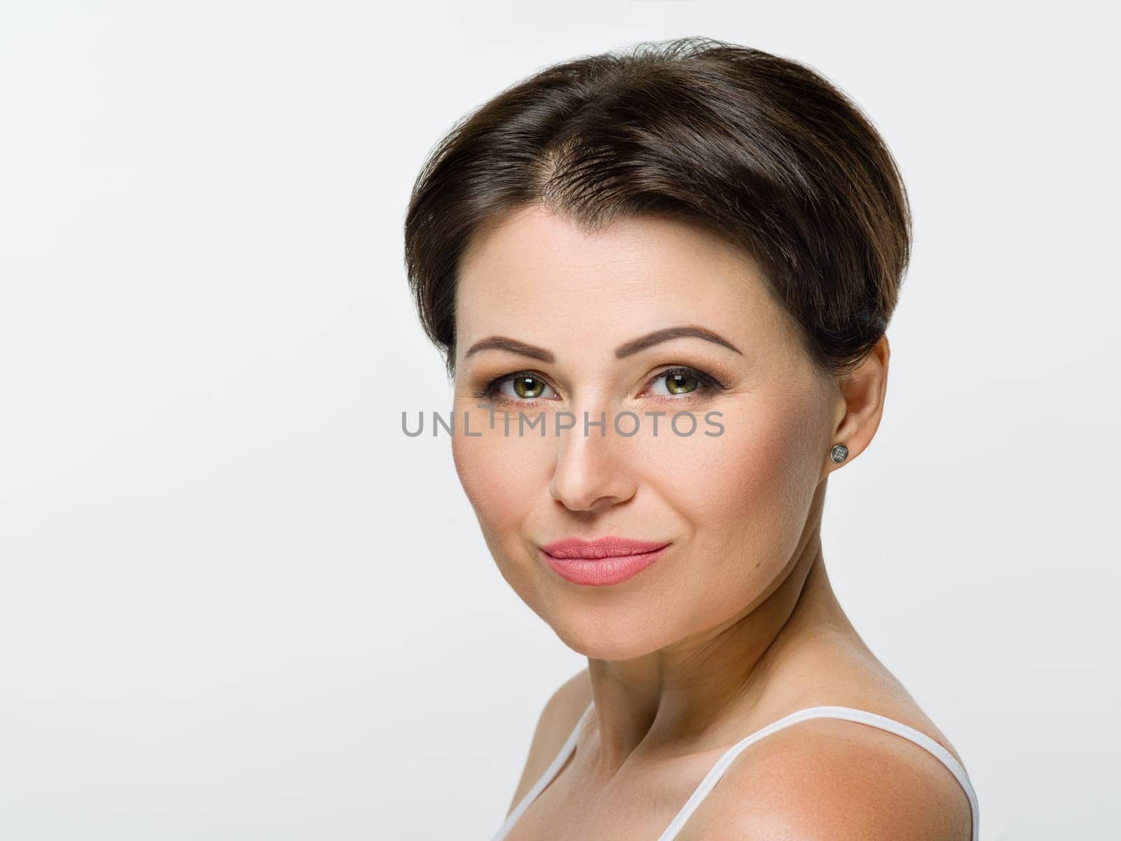 Head shot, beauty portrait of middle aged woman on white isolated background. Smiling female with hairstyle makeup looking at camera. Mature age, 40s, health, skin care, cosmetics concept