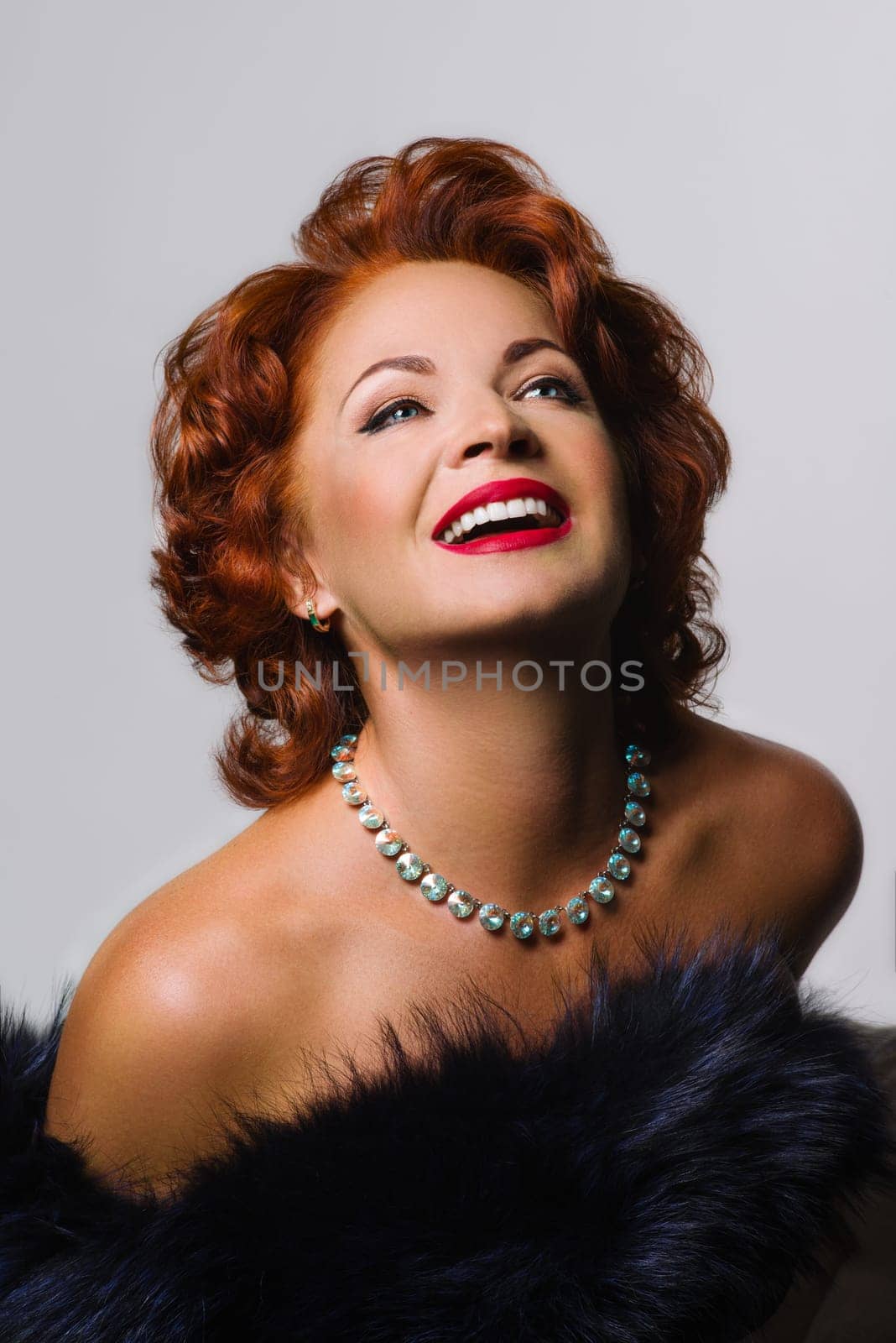 Portrait of middle aged red-haired woman in the image of Mereline Monroe, on white by VH-studio