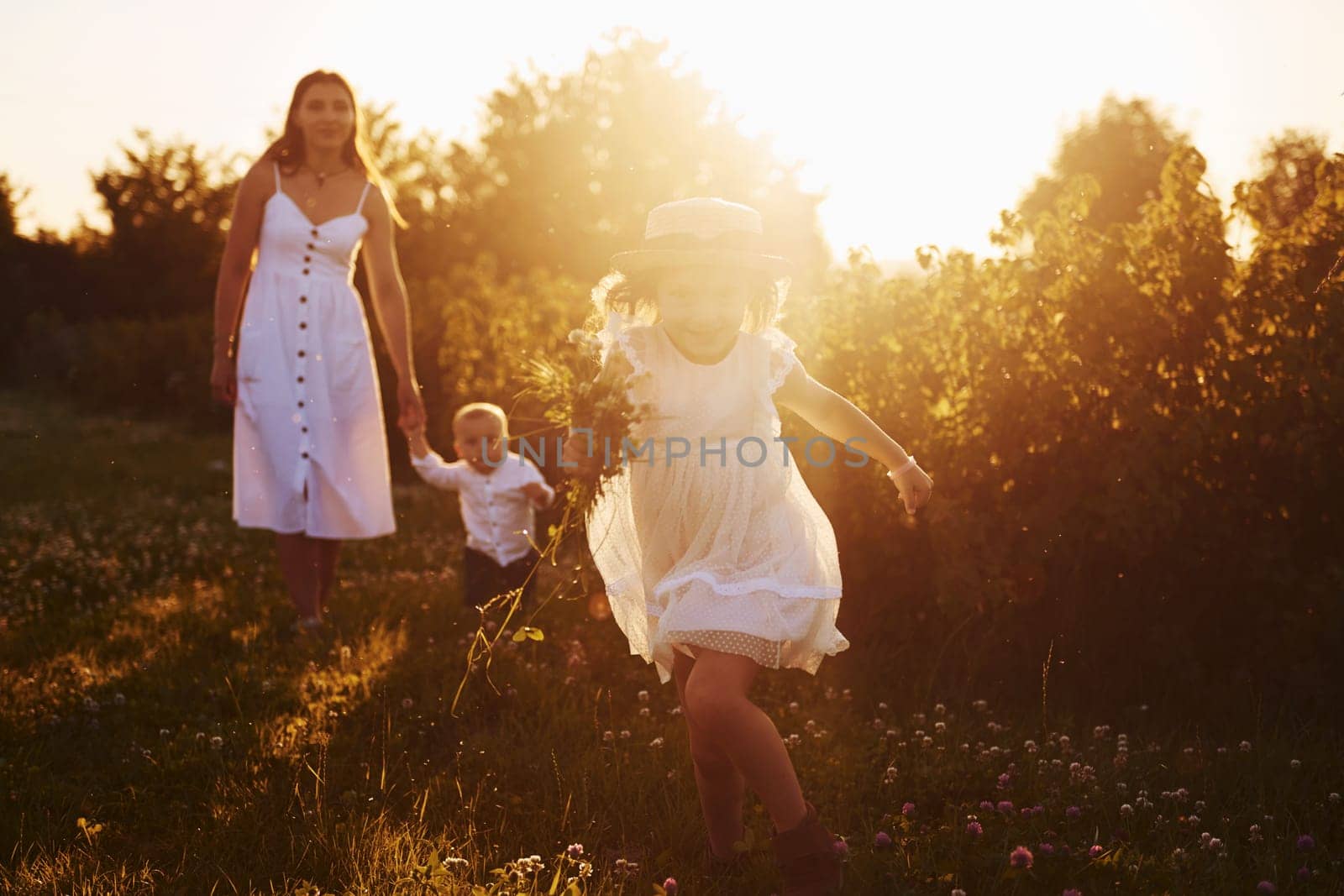 Beautiful lightbeam. Mother with boy and girl spending free time on the field at sunny day time of summer.