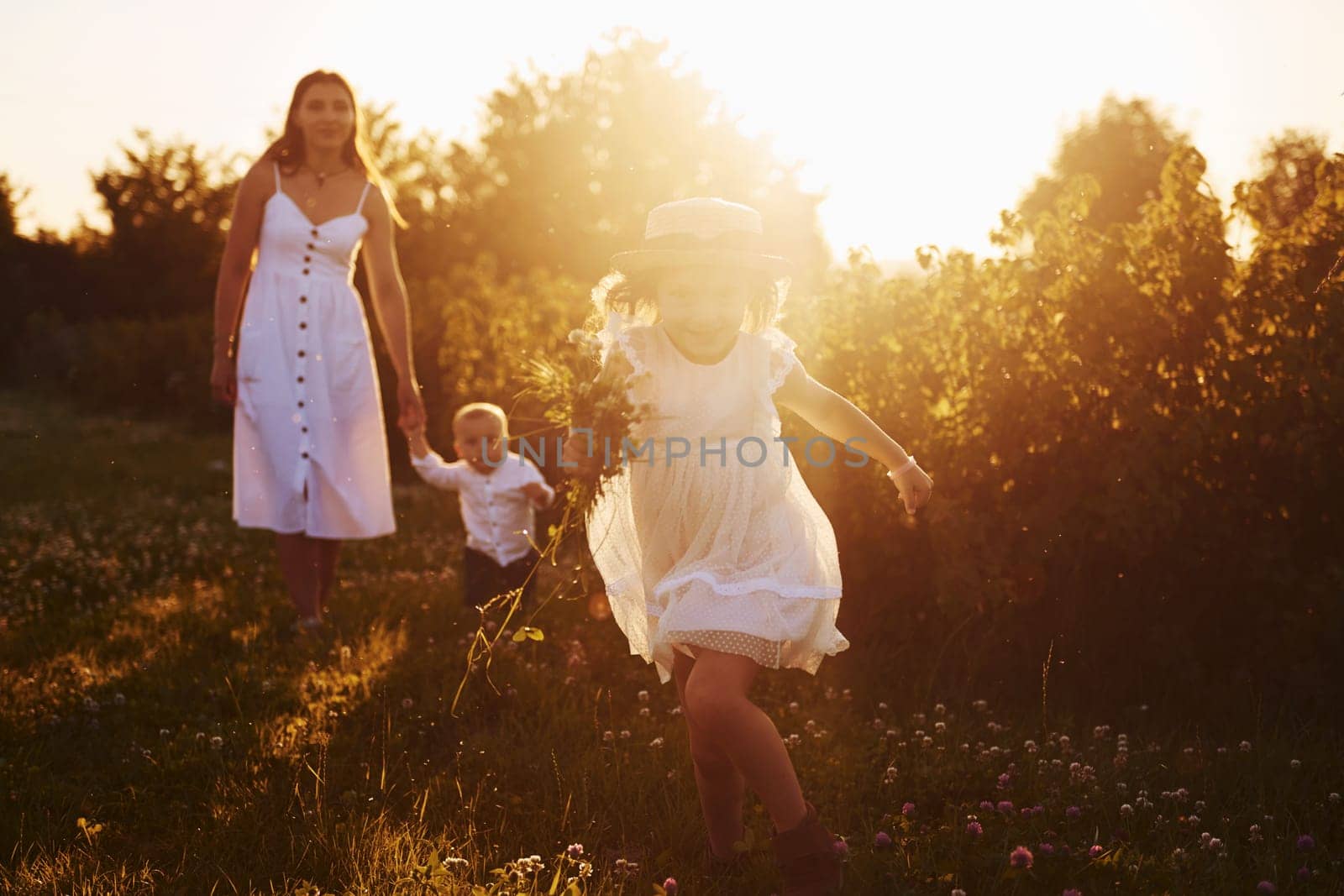 Beautiful lightbeam. Mother with boy and girl spending free time on the field at sunny day time of summer by Standret