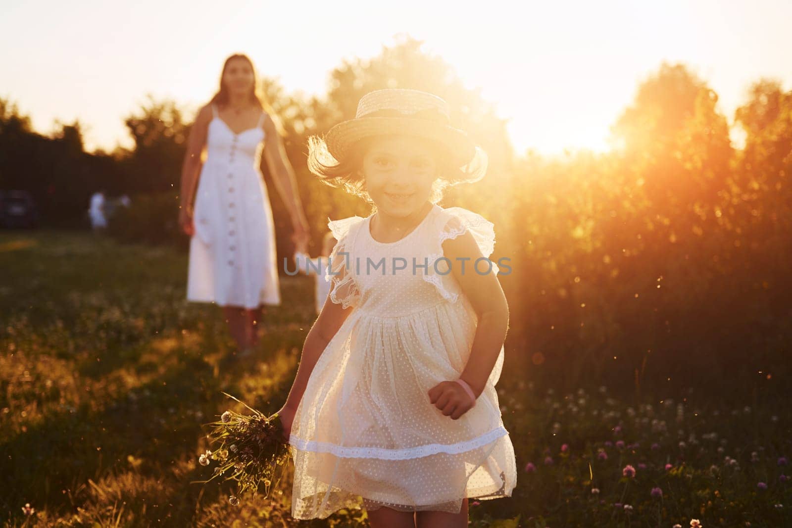 Beautiful lightbeam. Mother with boy and girl spending free time on the field at sunny day time of summer.