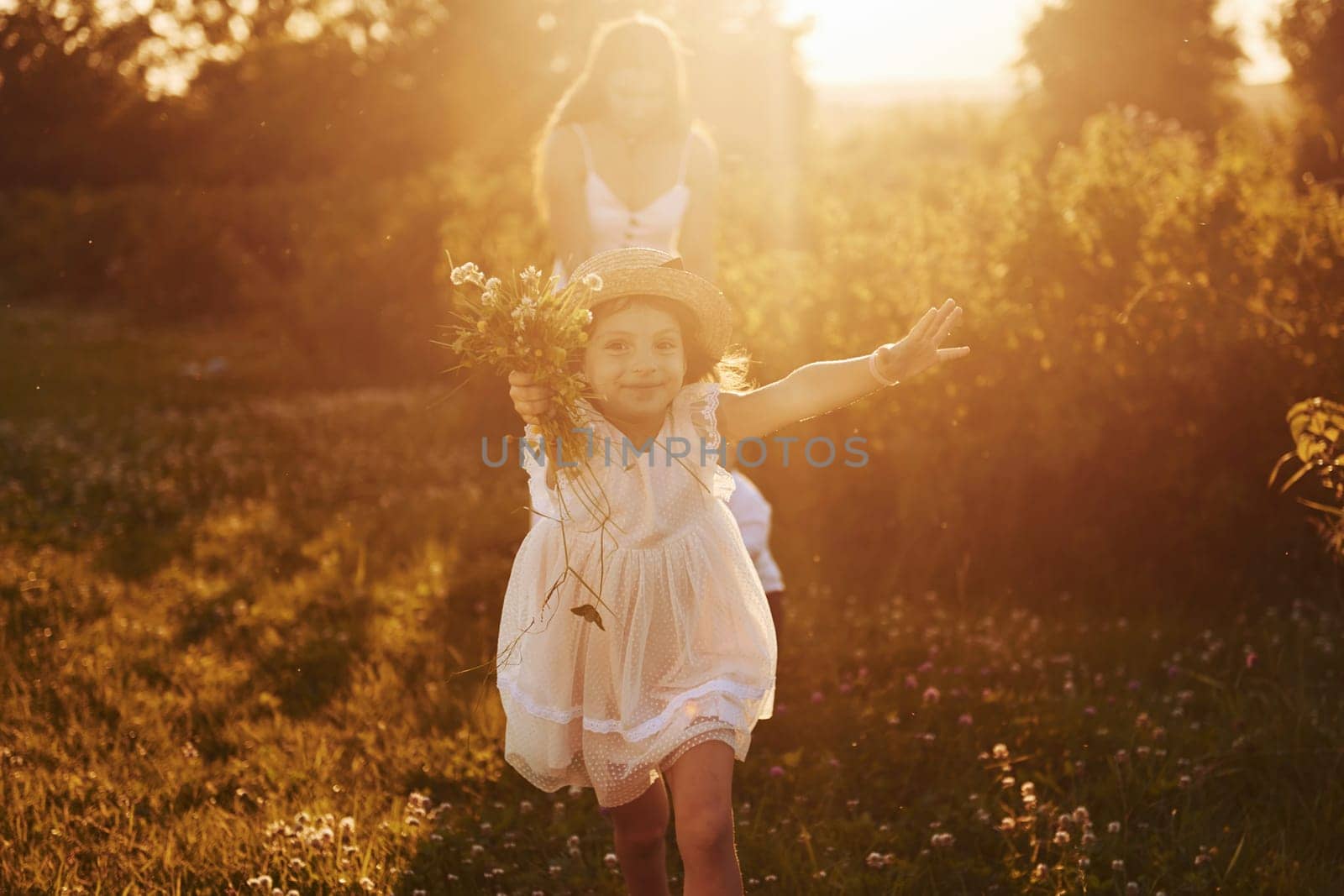 Beautiful lightbeam. Mother with boy and girl spending free time on the field at sunny day time of summer.