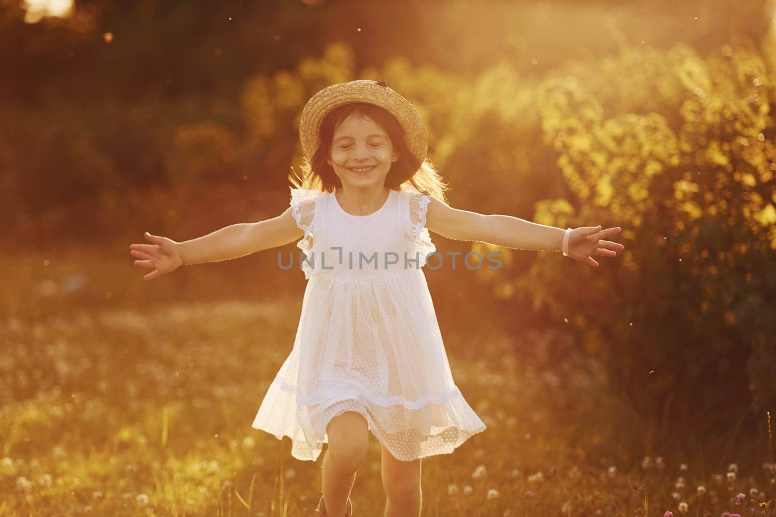Happy little girl in white dress have fun outdoors on meadow at summertime by Standret