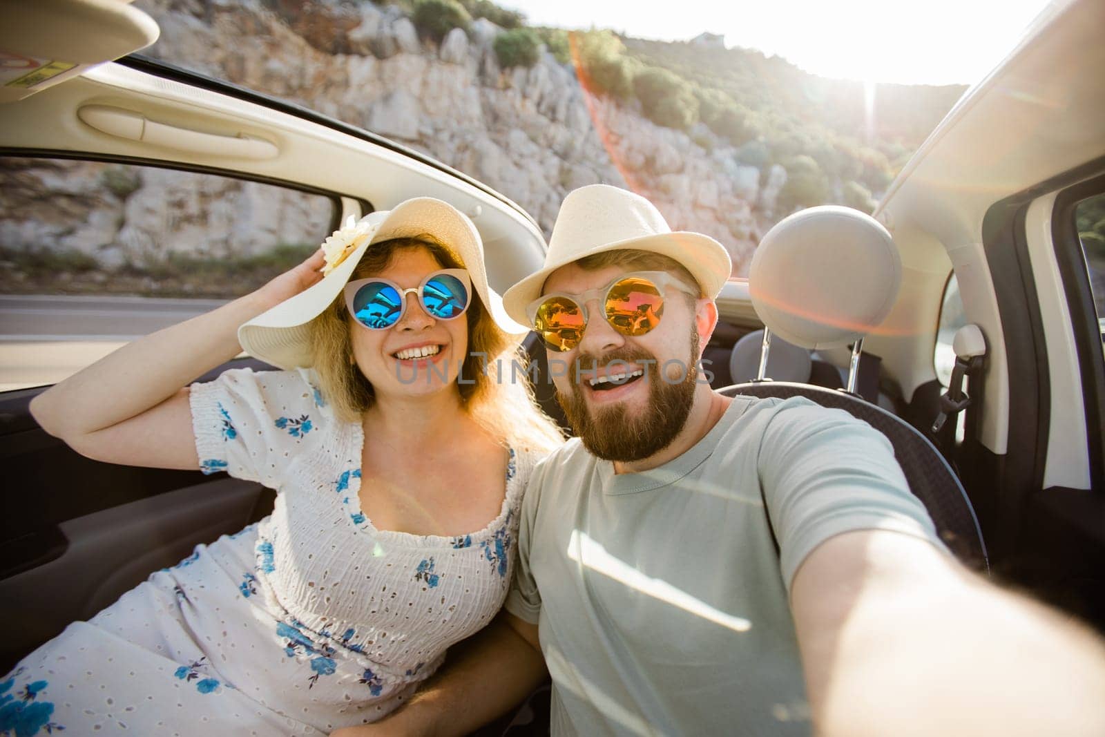 Happy beautiful couple in love taking a selfie portrait driving a convertible car on the road at vacation. Rental cars and vacation by Satura86