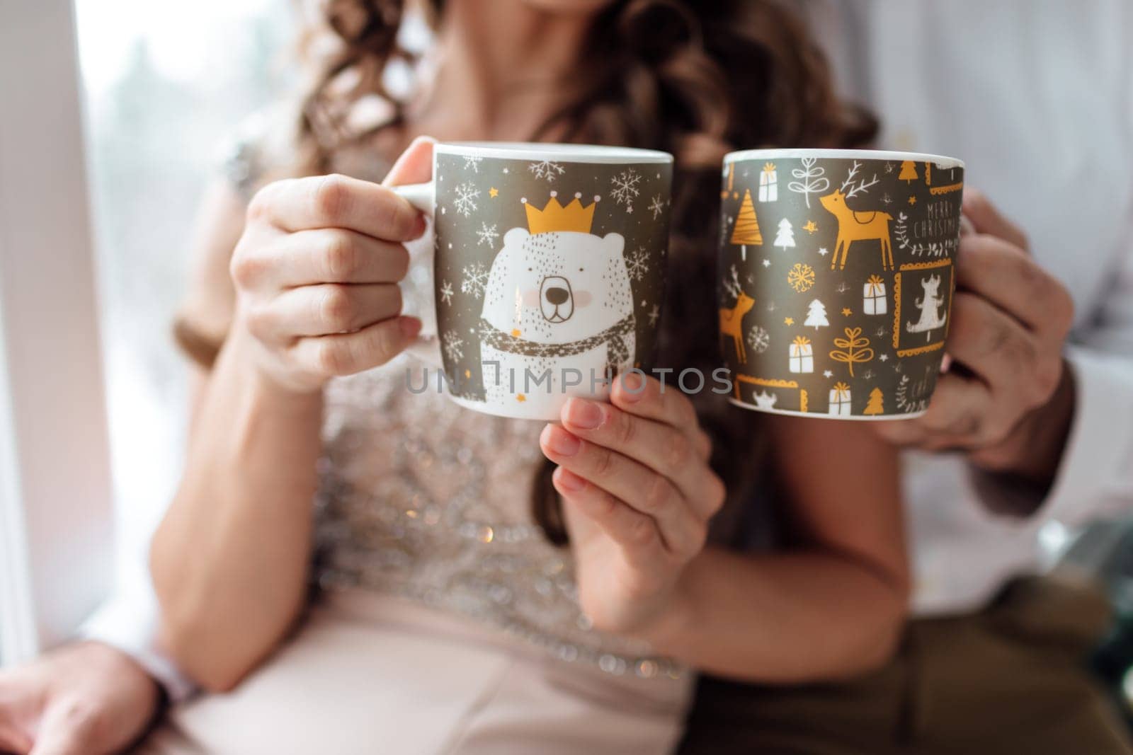 Christmas. Love. Home. hands of man and woman are holding with christmas decorations cups with hot coffee or tea.