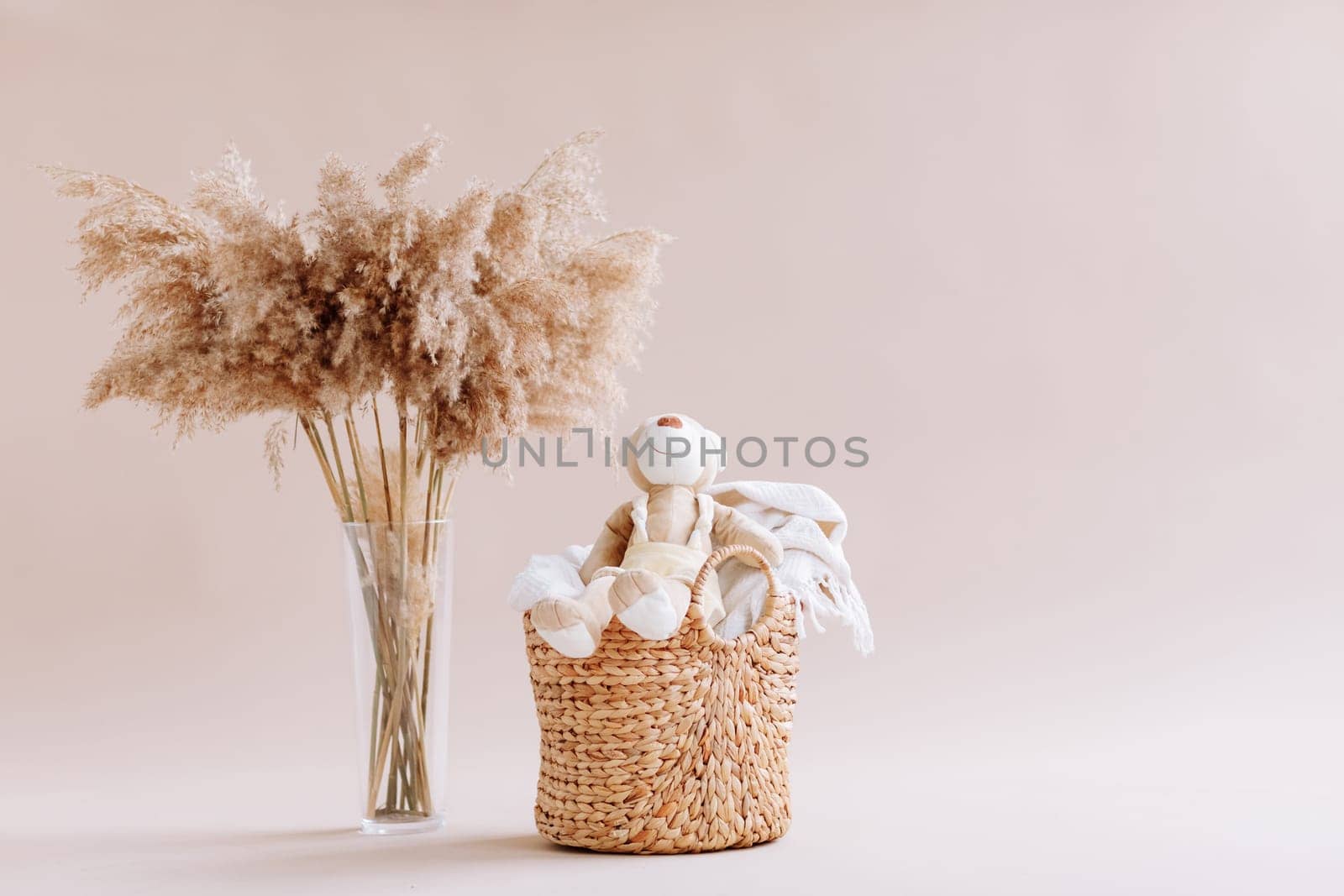 Interior of house of Natural accessories for home decor - dried plants in glass vase, wicker basket with teddy rabbit and plaid. Scandinavian cozy decor. copy space.