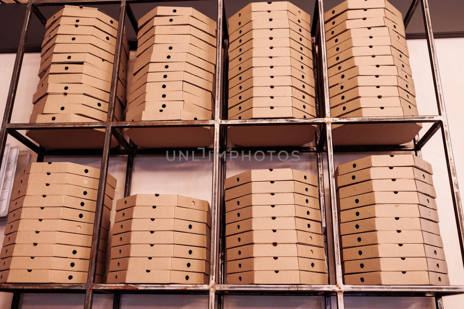 food delivery service. tall stacks of flat brown cardboard pizza boxes on metal shelf ready for delivery. craft packing boxes with pizza in stock in storage.