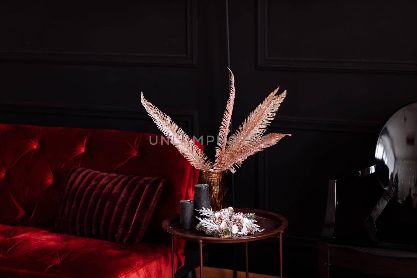 decorated room with a red velvet sofa and a vase on the table.