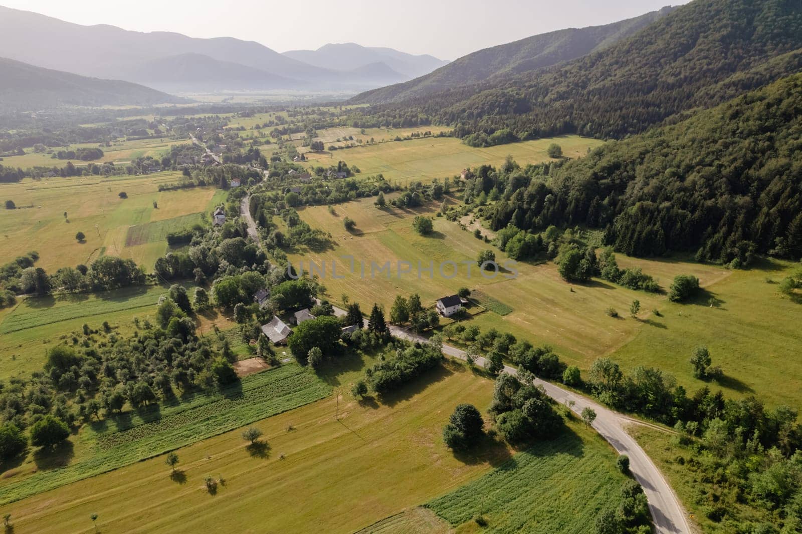 Top view of hilly local green forest in light fog and mountain road. Green forest landscape.