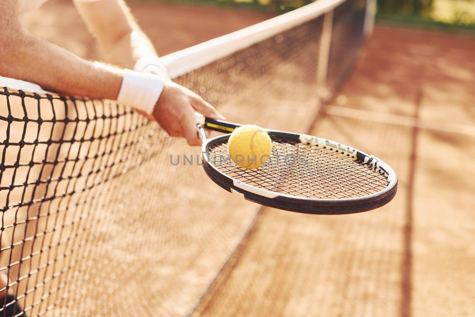 Close up view of senior man in white shirt and black sportive shorts that is on tennis court by Standret
